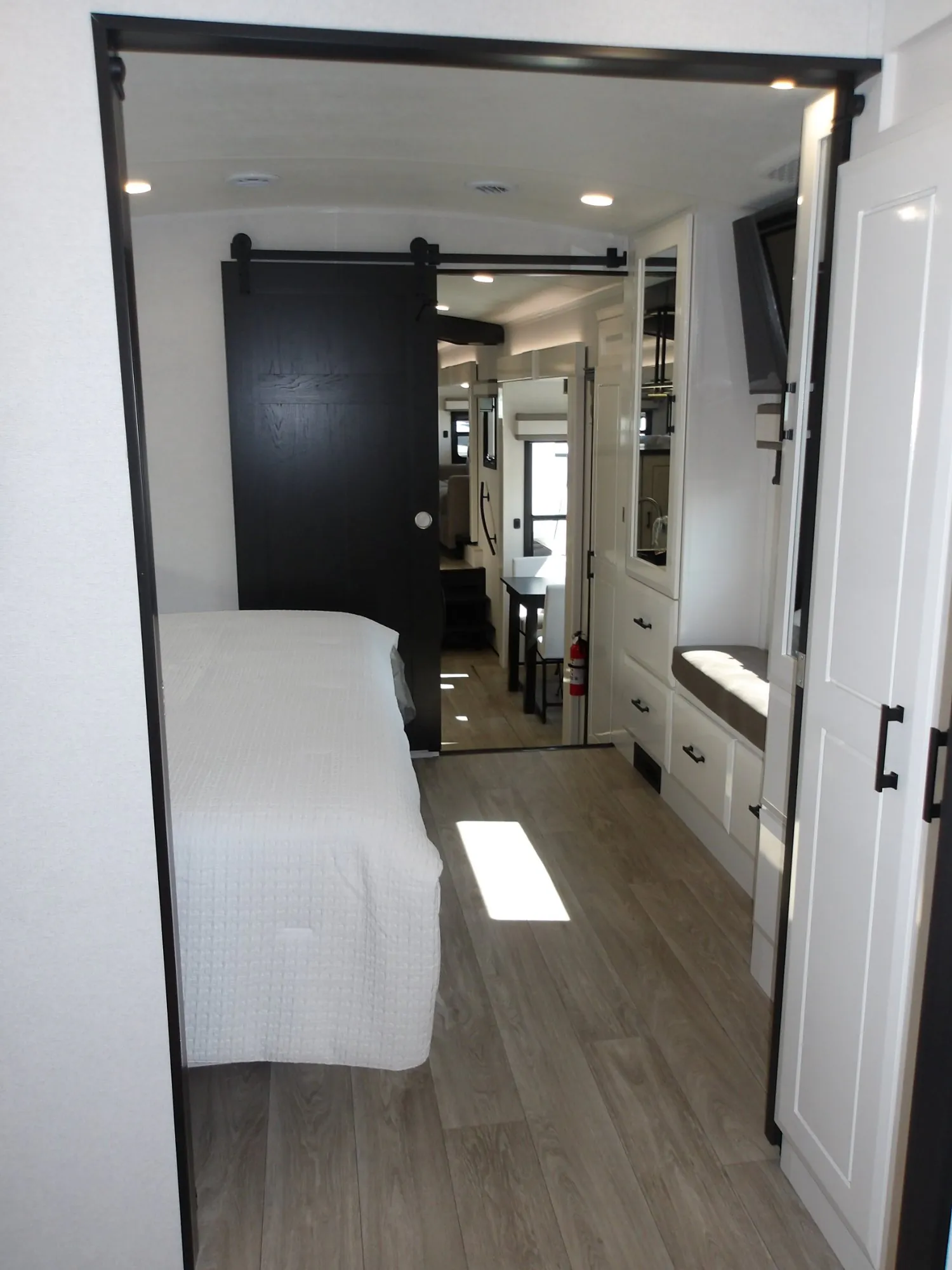 2027 Jayco Pinnacle 39FLOK — Fifth wheel bedroom with bed, dresser, sliding door, and a view toward the dining and living areas