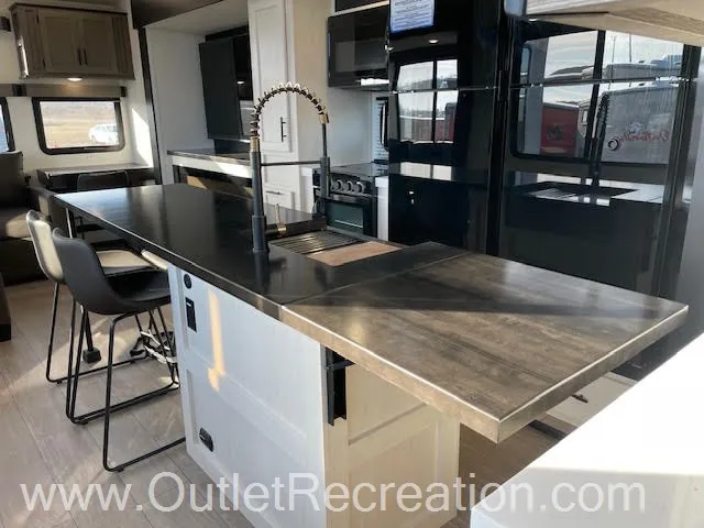 2026 Forest River Arctic Wolf 38LEAH.G — Kitchen island with farmhouse sink, counter workspace, refrigerator, and adjacent bar stools