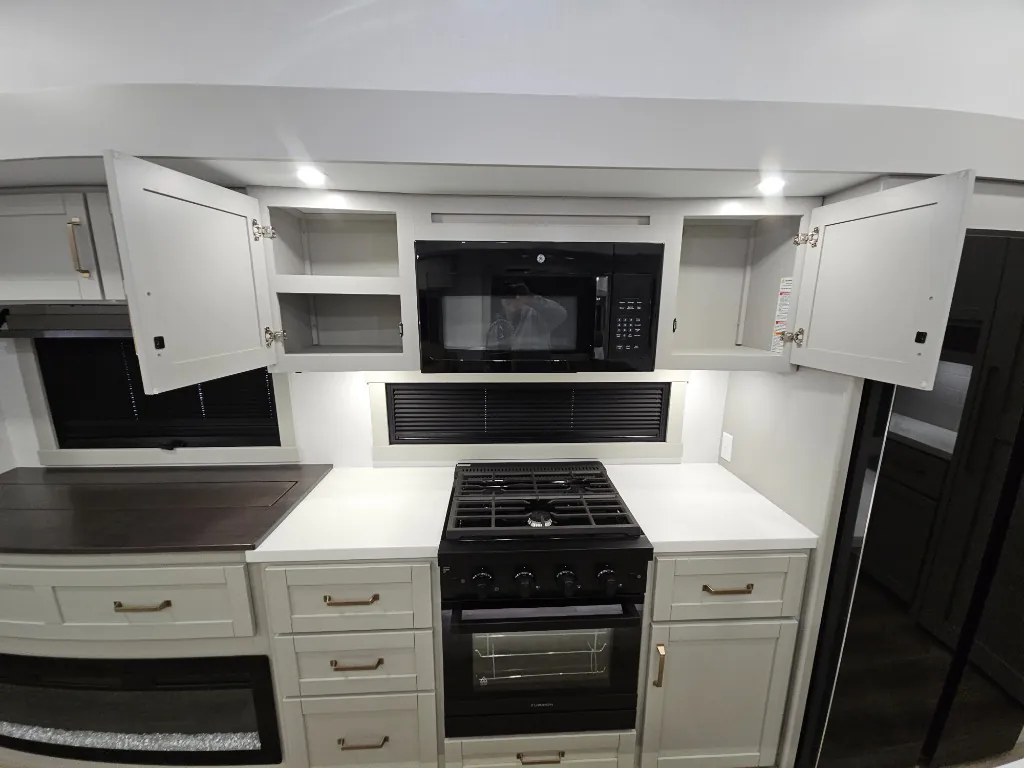 2026 Brinkley Model Z 3515 — Kitchen cooking wall with gas range, oven, microwave, open overhead cabinets, counters, and refrigerator edge