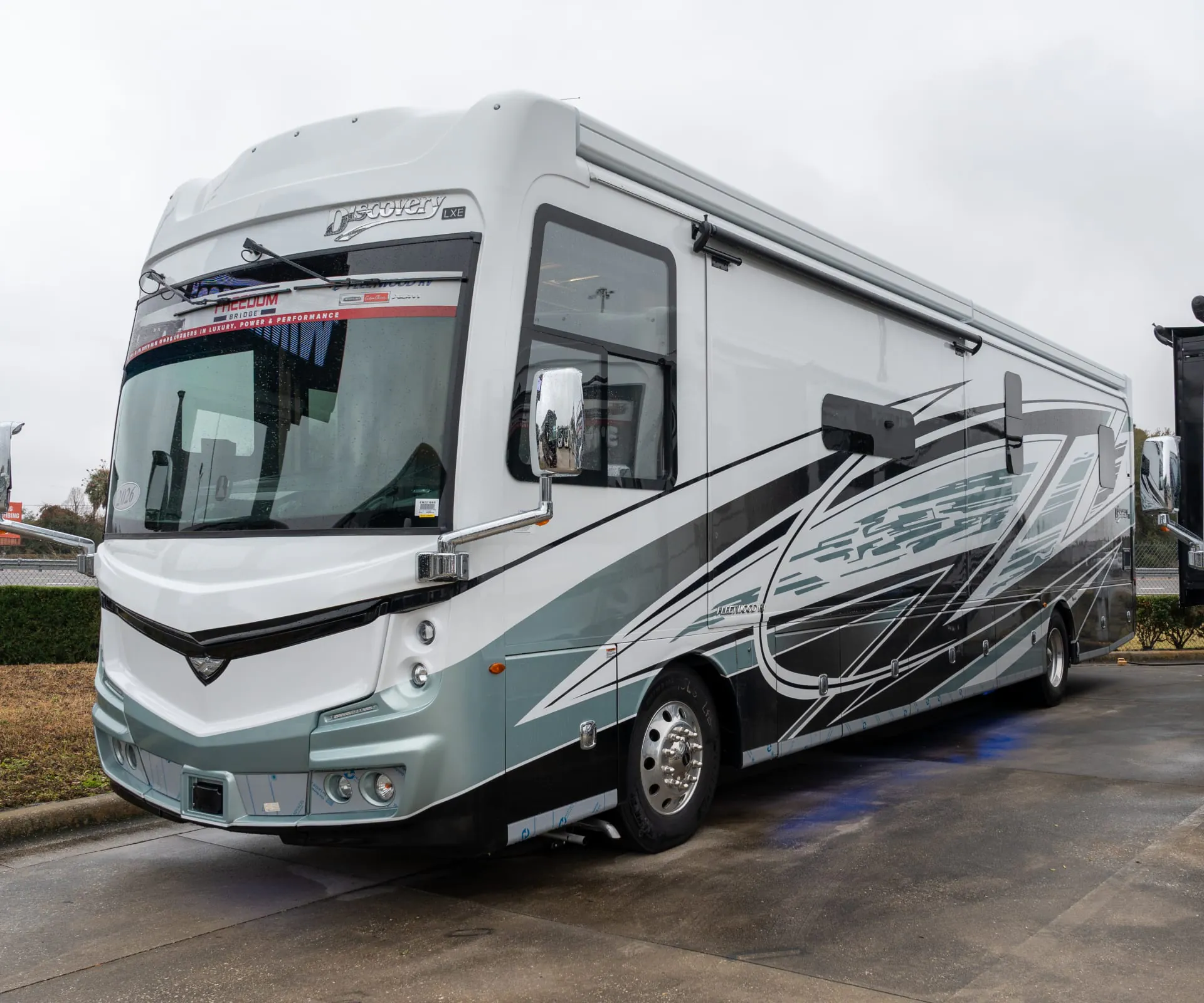 2026 Fleetwood Discovery LXE 40G — Exterior photograph clearly shows the motorhome's front and side body, windows, wheels, graphics, and awning hardware