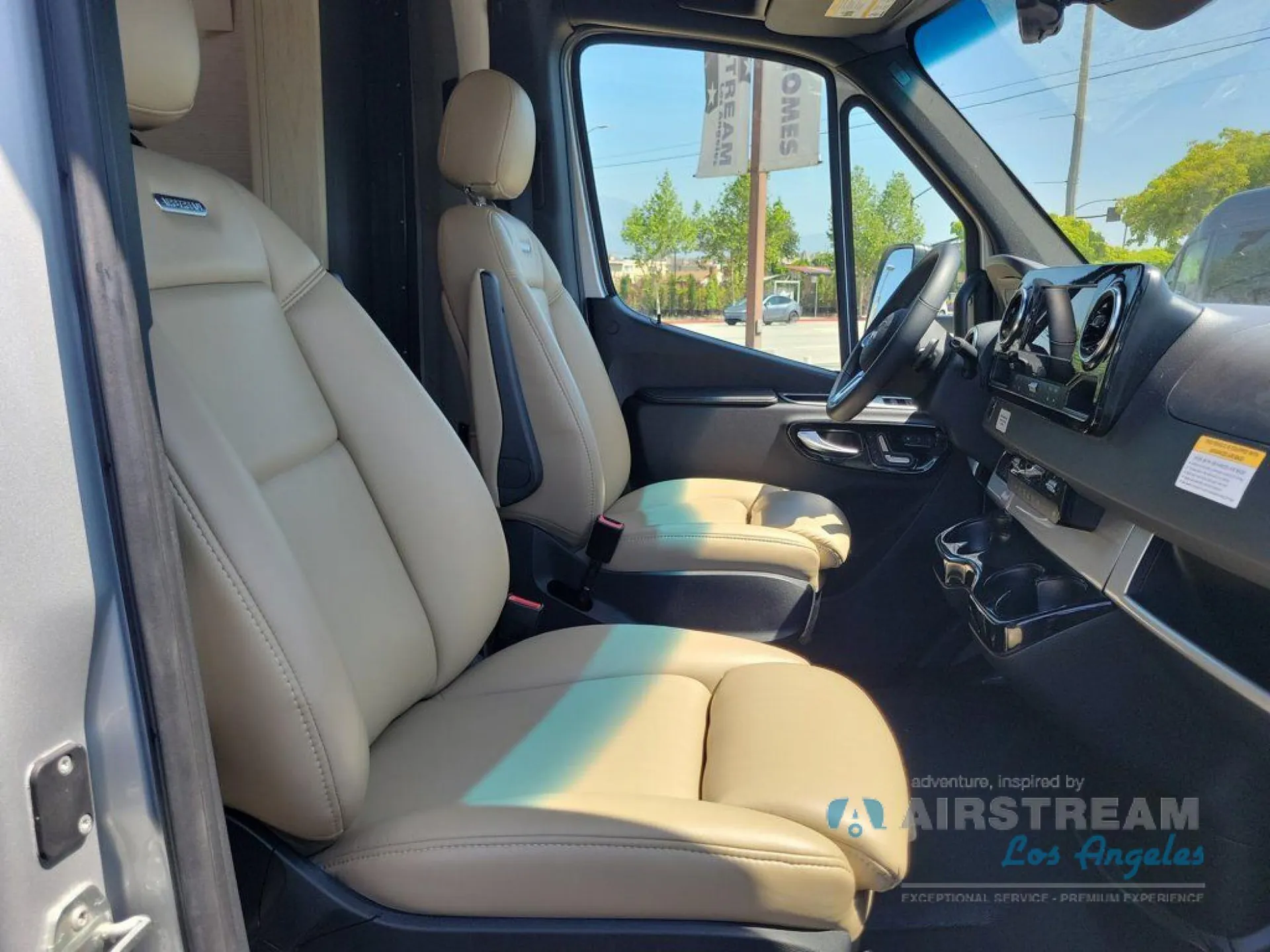 2026 Airstream Atlas Murphy Suite — Class B van front cabin with cream driver and passenger seats, steering wheel, dashboard, and side window