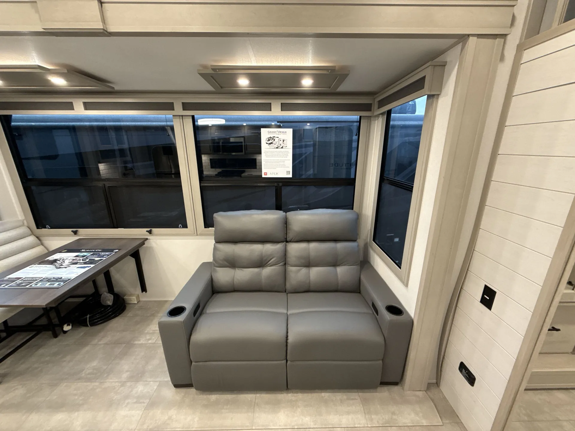 2026 Grand Design Solitude 391DL — Pair of theater recliners beside a dinette table, surrounded by large RV windows