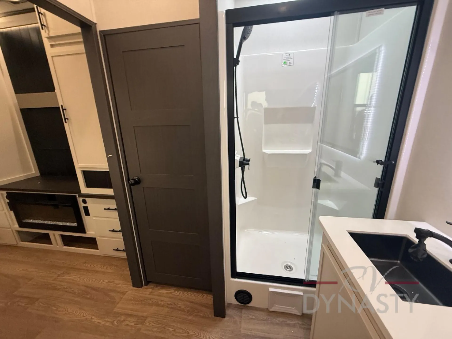 2027 Forest River Sanibel 40BUNK — Bathroom shower enclosure and vanity sink with a toilet-room door and cabinetry visible nearby
