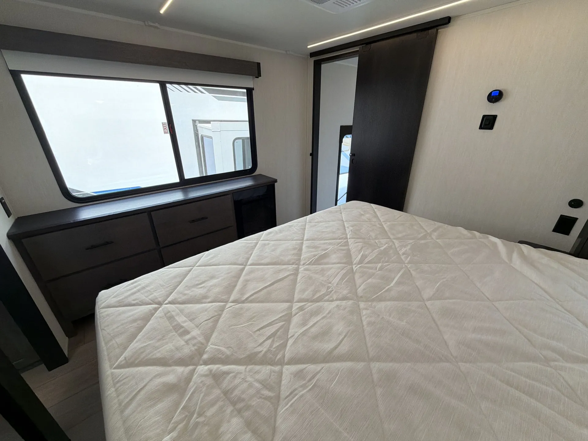 2026 Forest River Arctic Wolf 38LEAH.G — Main bedroom with a large made bed, dresser, window, and sliding closet door