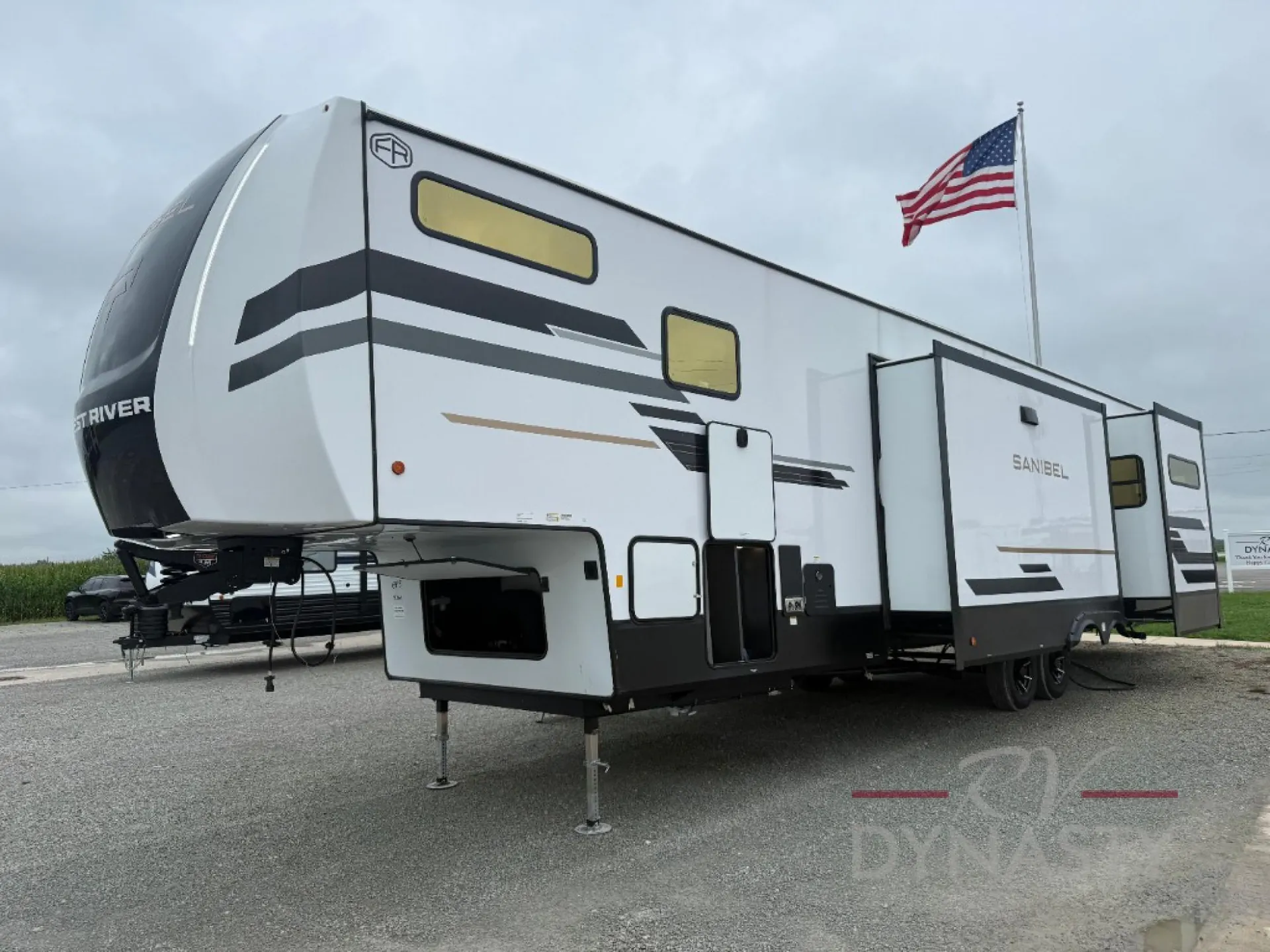 2027 Forest River Sanibel 40BUNK — The exterior side and front of the fifth-wheel RV, including slides, windows, hitch, and storage access