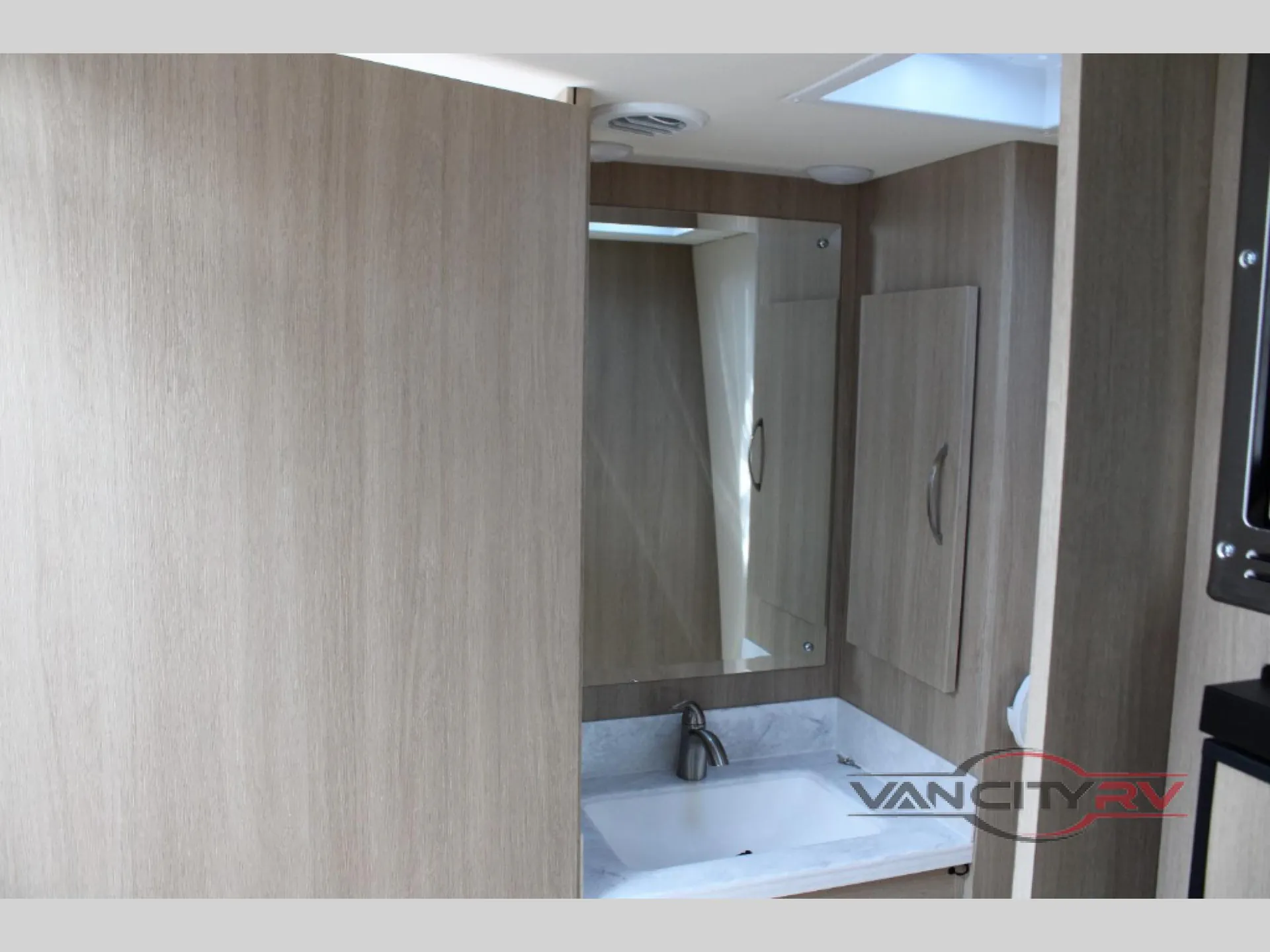 2025 Chinook RV Maverick SS — Compact bathroom vanity with sink, faucet, mirror, and surrounding storage cabinetry