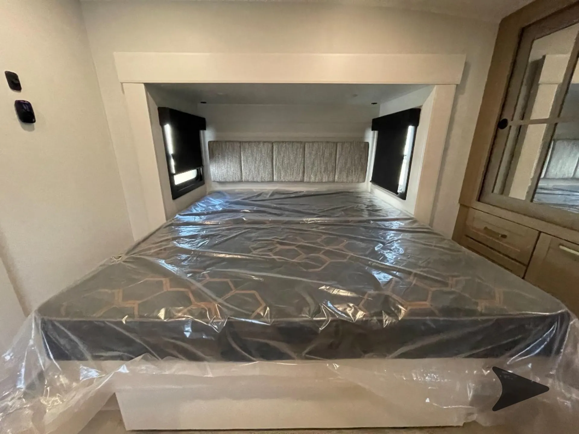 2027 Jayco Eagle 355MBQS — Main bedroom with a plastic-covered bed, upholstered headboard, side windows, and mirrored wardrobe