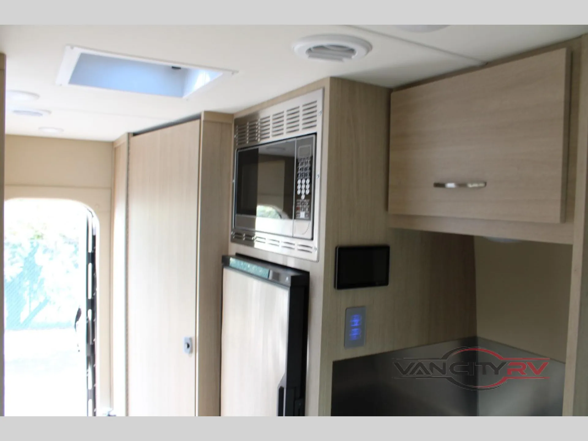 2025 Chinook RV Maverick SS — Class B van kitchen wall with microwave, refrigerator, countertop, upper cabinets, and control panel