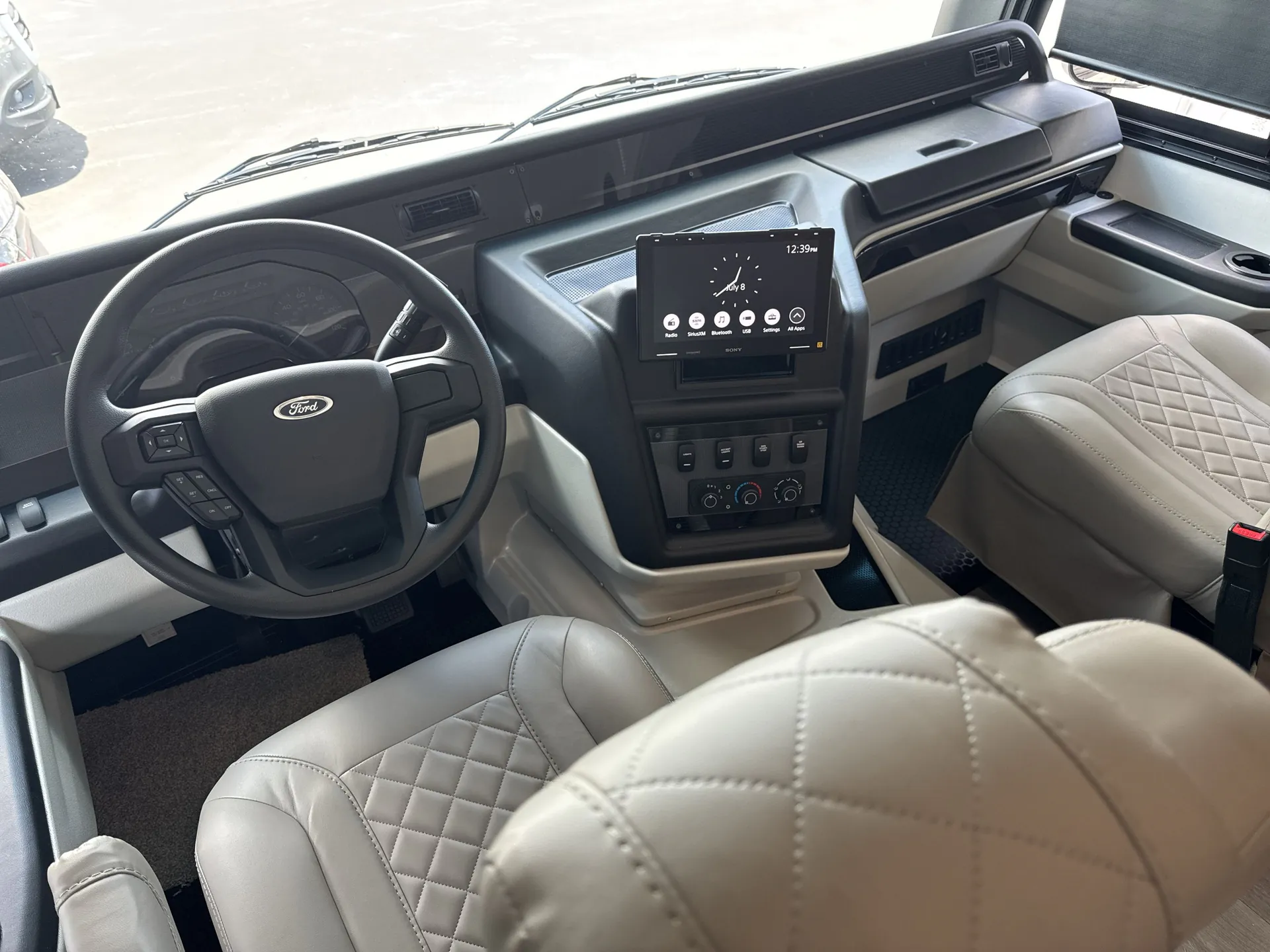 2027 Jayco Alante 29F — Class A motorhome cockpit with steering wheel, instrument cluster, dashboard controls, center display, windshield, and passenger seat