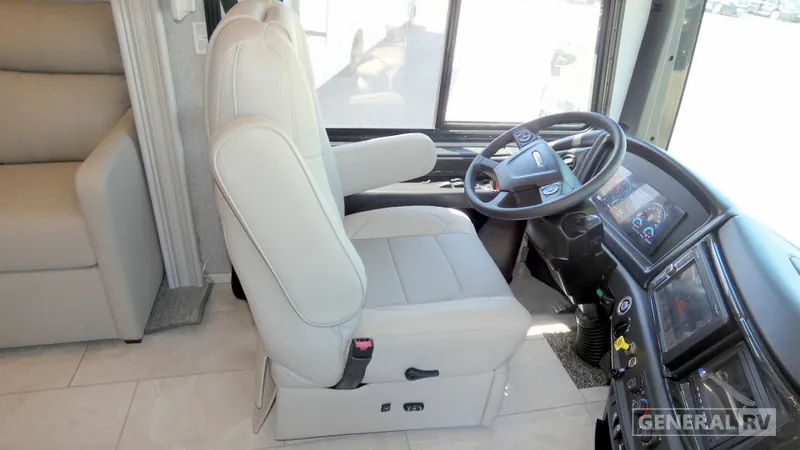 2027 Fleetwood Discovery LXE 40M — Motorhome cockpit with driver seat, steering wheel, instrument display, dashboard controls, and windshield