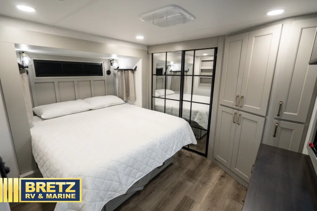 2026 Brinkley Model G 3950 — Fifth wheel bedroom with a made bed, mirrored wardrobe doors, cabinets, and dresser