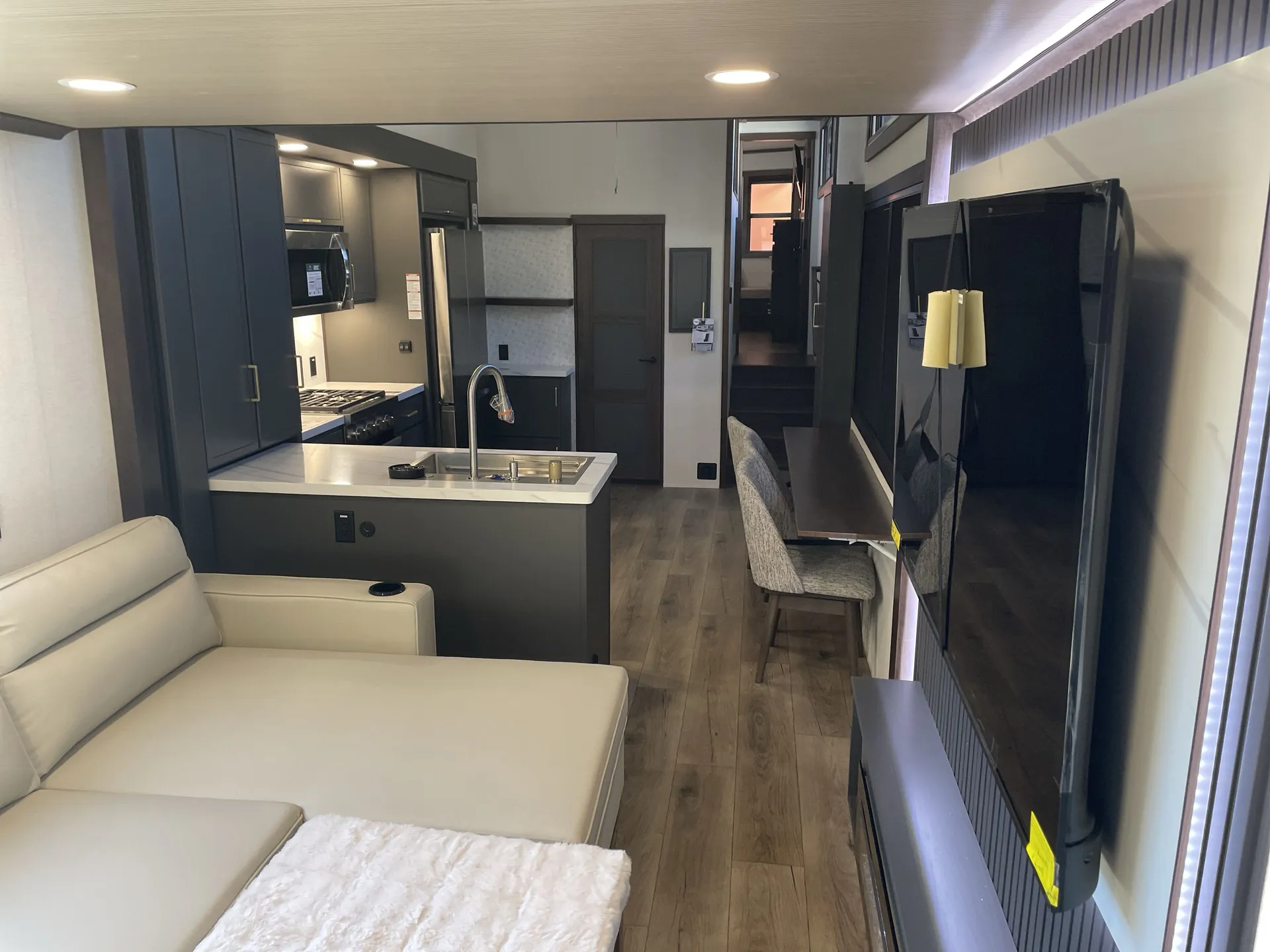 2026 Forest River Cedar Creek Cottage 41FWC — Fifth wheel overview with sectional living area, kitchen island and appliances, dining chairs, television, and rear stairs