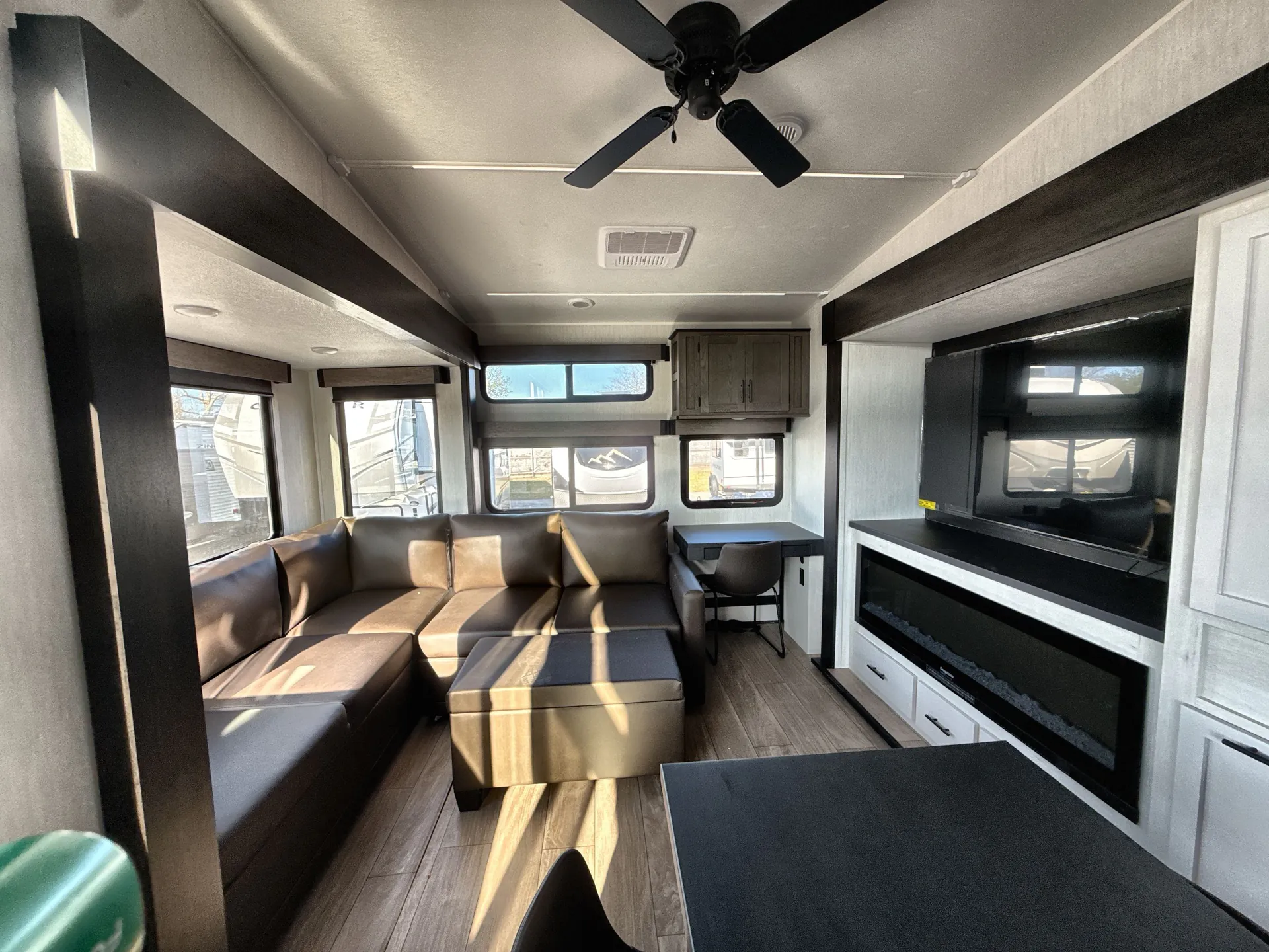 2026 Forest River Arctic Wolf 38LEAH.G — Fifth wheel living area with sectional sofa, large television, entertainment cabinet, and nearby dining table
