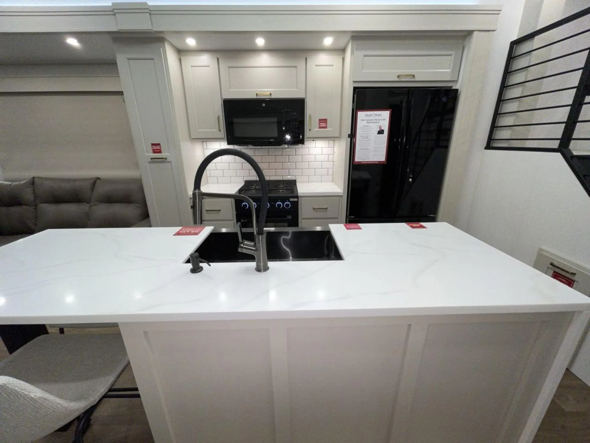 2026 Grand Design Foundation 42GD — Kitchen island sink and faucet facing a range, microwave, backsplash, and refrigerator with surrounding cabinetry