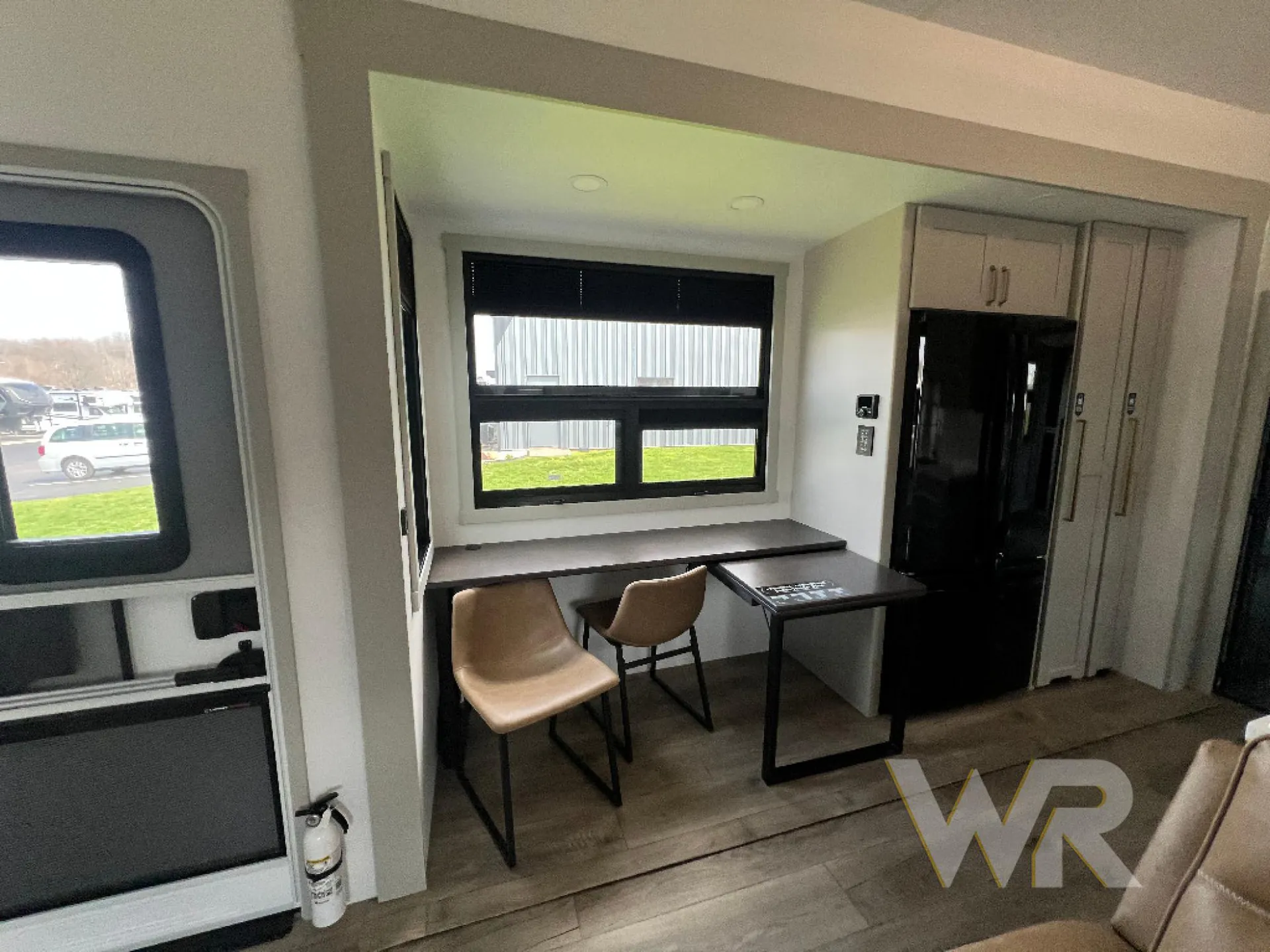 2026 Brinkley Model G 3950 — Dining nook with two chairs, a small table, and window seating beside the refrigerator and edge of a sectional