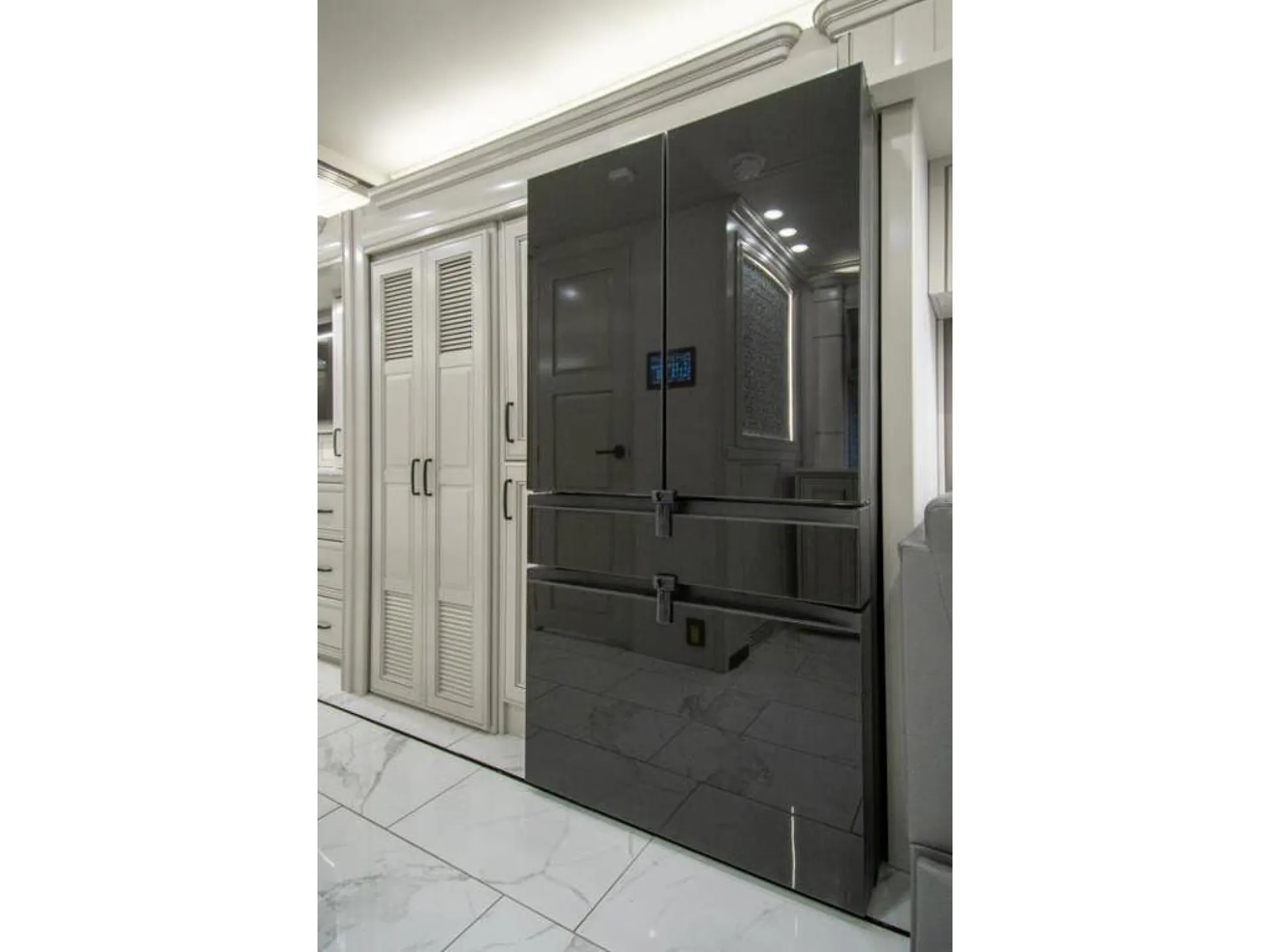 2026 American Coach American Dream 45A — Large black refrigerator beside tall pantry-style cabinets in the motorhome kitchen
