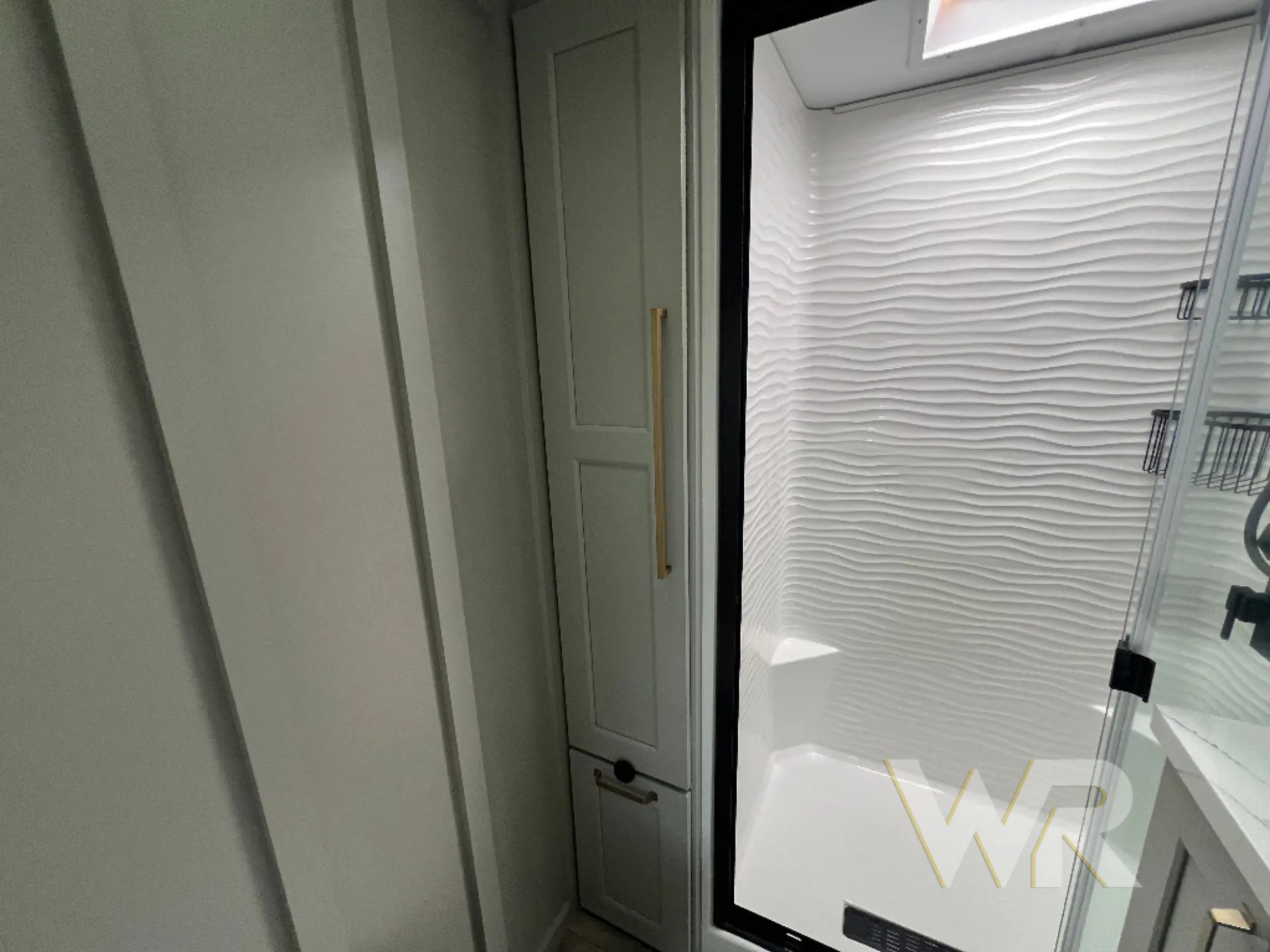 2026 Brinkley Model G 3950 — Bathroom shower with textured white wall, glass door, and adjacent tall storage cabinet