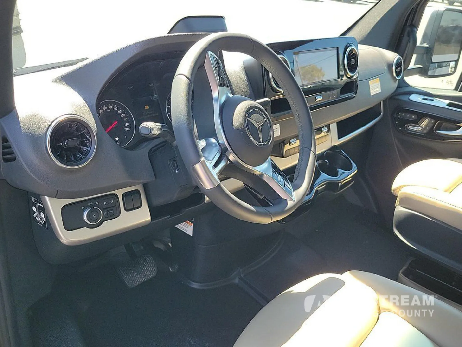 2026 Airstream Atlas Murphy Suite — Class B van cockpit with steering wheel, instrument panel, infotainment screen, climate controls, and front passenger seat