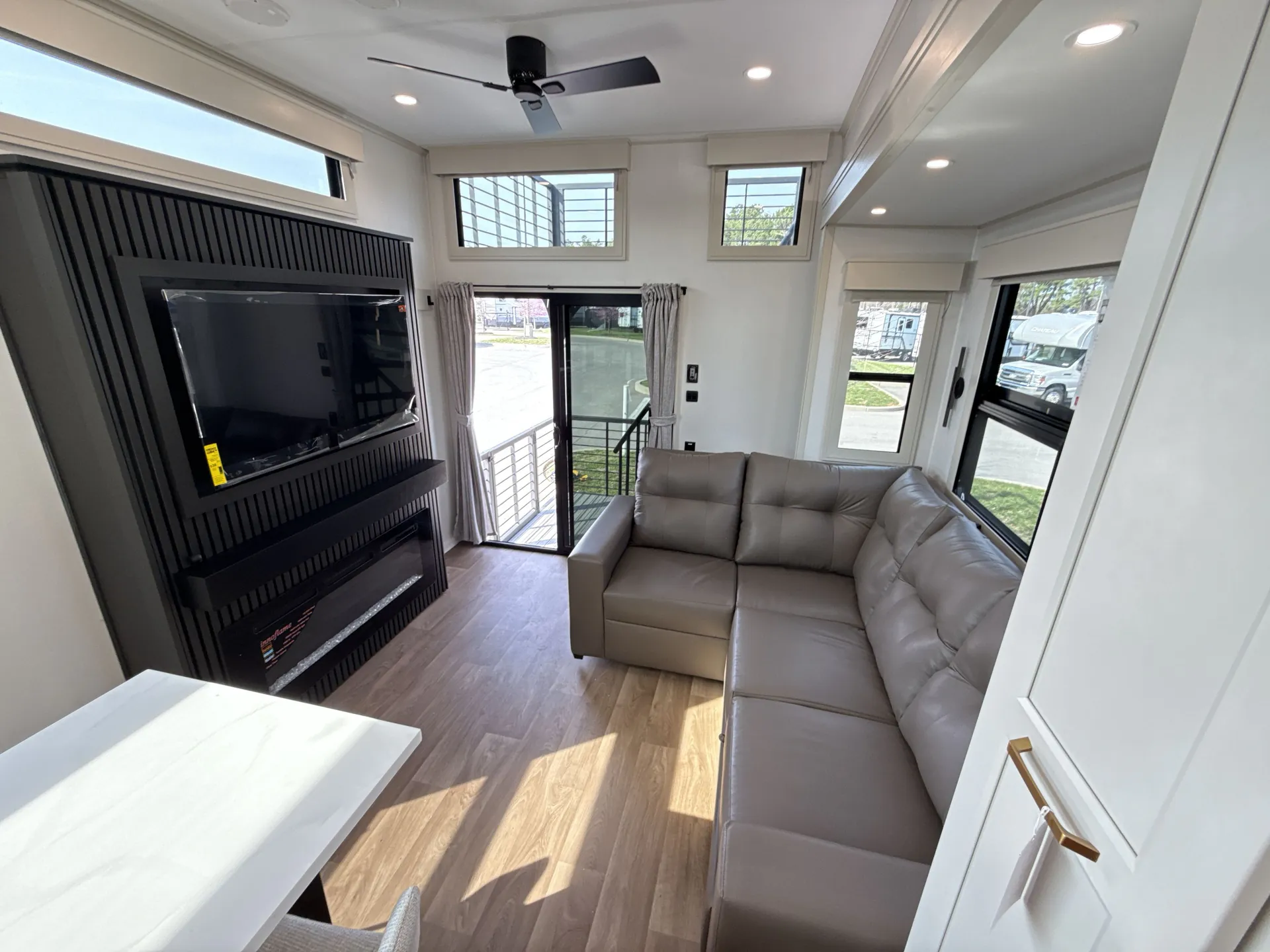 2026 Grand Design Foundation 42GD — Destination trailer living room with sectional sofa, TV fireplace wall, entry door, and edge of dining table