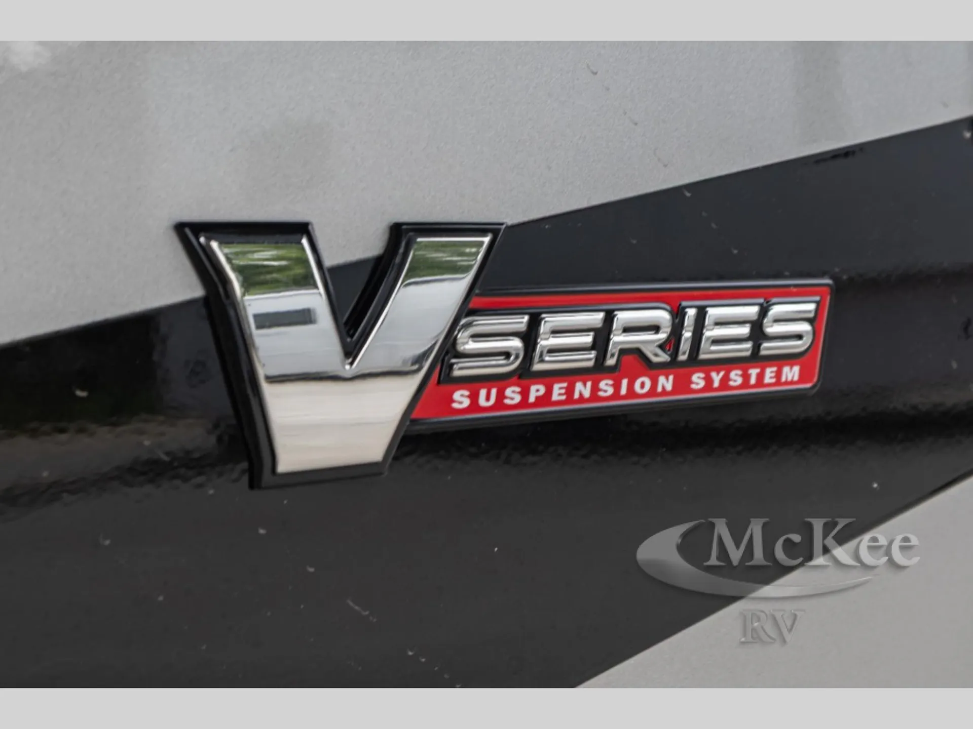 2027 Fleetwood Discovery LXE 40M — Close-up photograph visibly shows an exterior V-Series suspension-system badge, identifying an exterior mechanical feature
