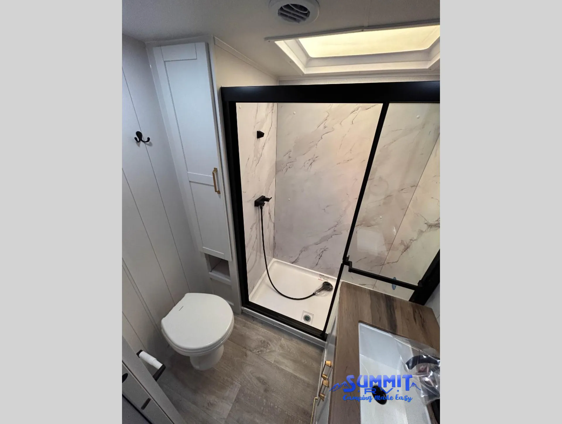 2027 Jayco Eagle 355MBQS — RV bathroom with enclosed glass shower, toilet, vanity edge, wall cabinet, and roof skylight