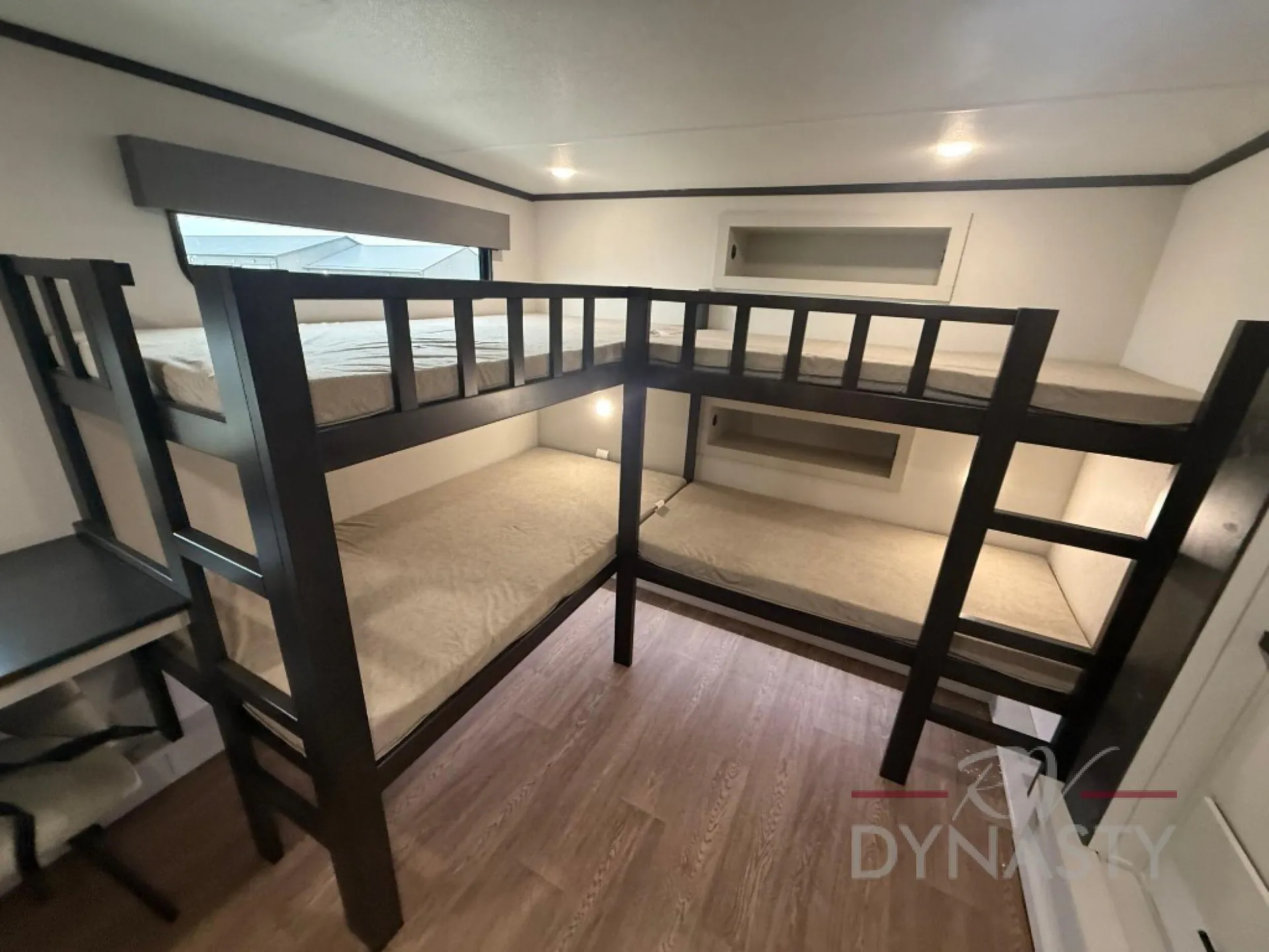 2027 Forest River Sanibel 40BUNK — Bunkhouse sleeping area with two levels of framed beds, ladders, windows, and recessed wall shelves