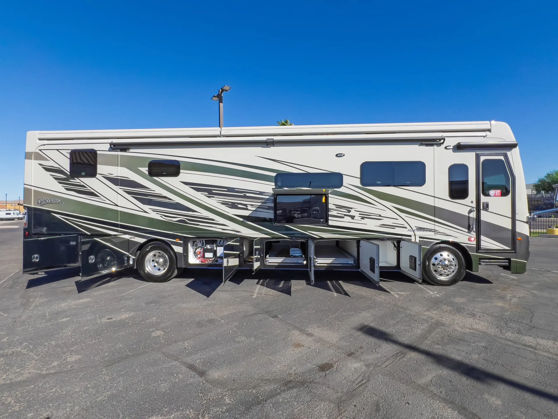 2027 Fleetwood Discovery LXE 40M — The motorhome exterior with multiple open lower storage compartments