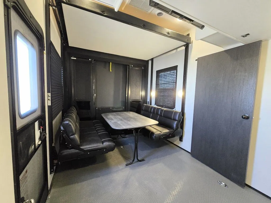 2025 Dutchmen Voltage 4225 — Toy-hauler garage configured with opposing bench seats and a freestanding table over a textured cargo floor