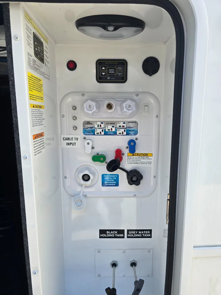 2026 Jayco North Point 377RLBH — Exterior utility panel visibly shows water connections, tank controls, cable input, and holding-tank valves