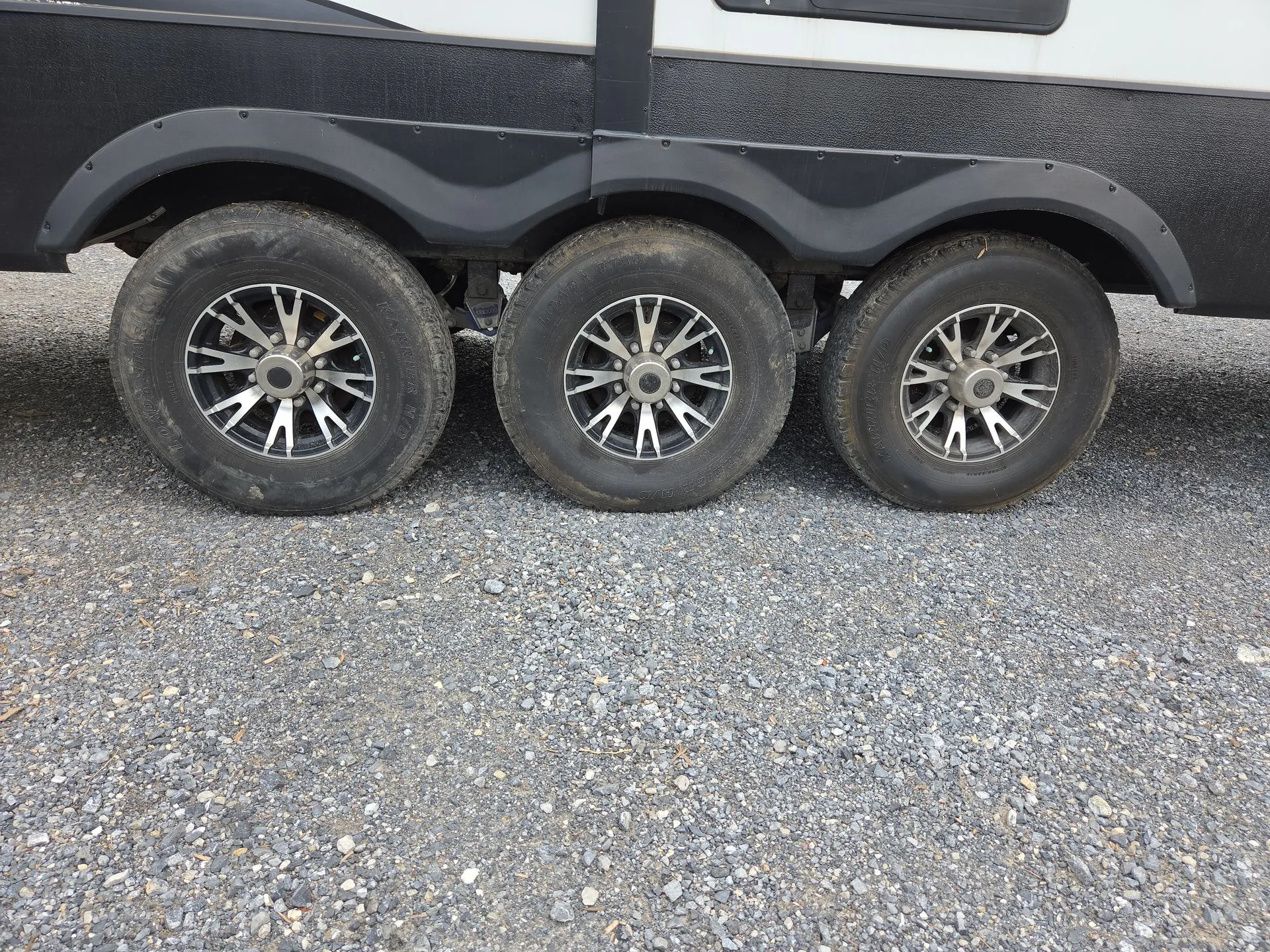 2022 Dutchmen Voltage 4225 — Close-up photograph clearly shows the RV's exterior triple-axle wheels and wheel wells