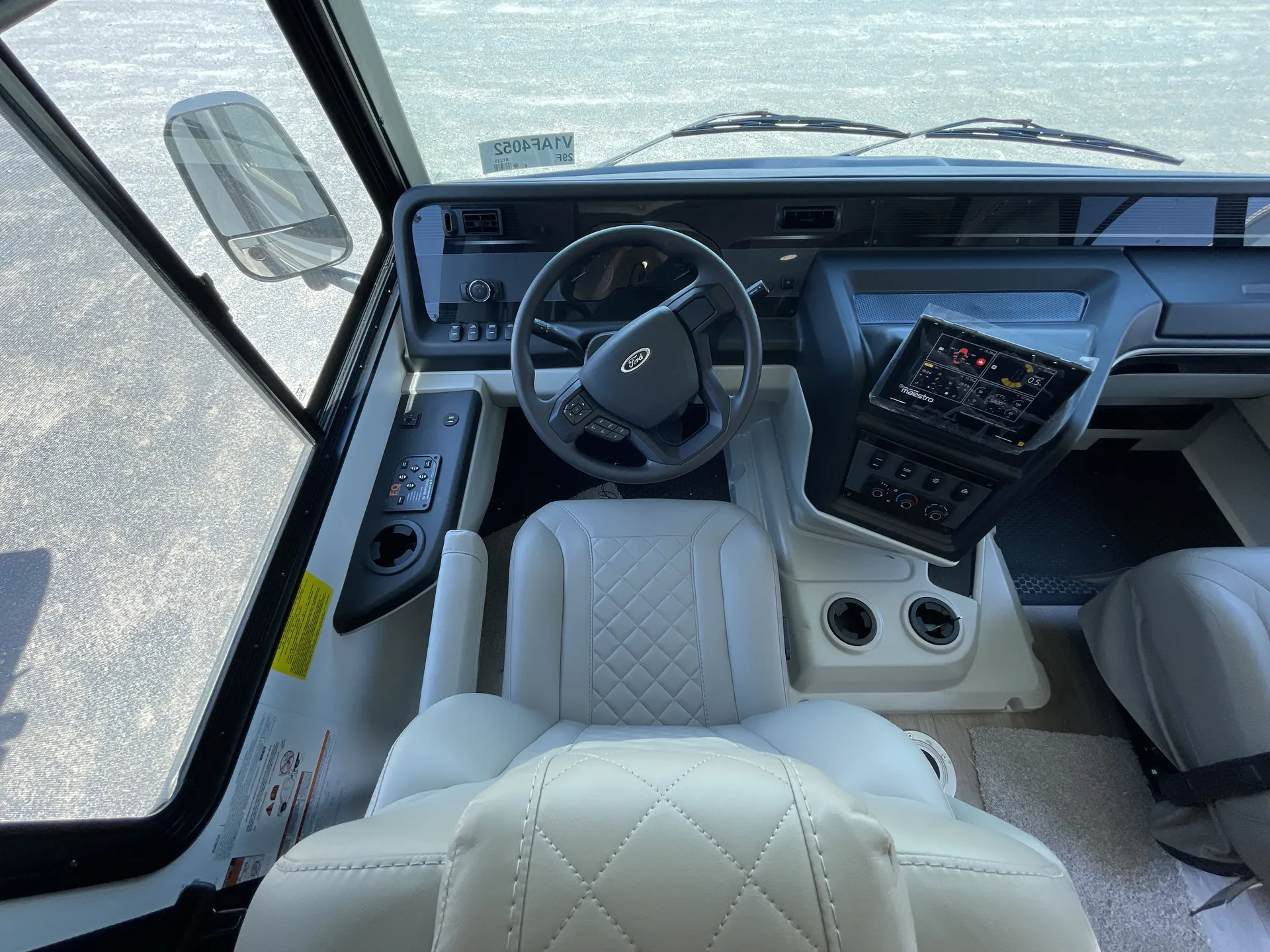 2027 Jayco Alante 29F — Class A cockpit with steering wheel, driver seat, dashboard controls, windshield, and center infotainment display