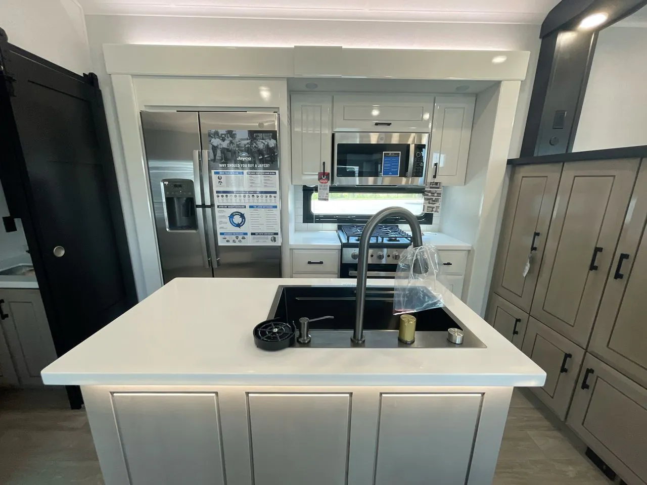 2027 Jayco Pinnacle 39FLOK — Fifth wheel kitchen island with sink faces a refrigerator, microwave, range, and surrounding cabinetry