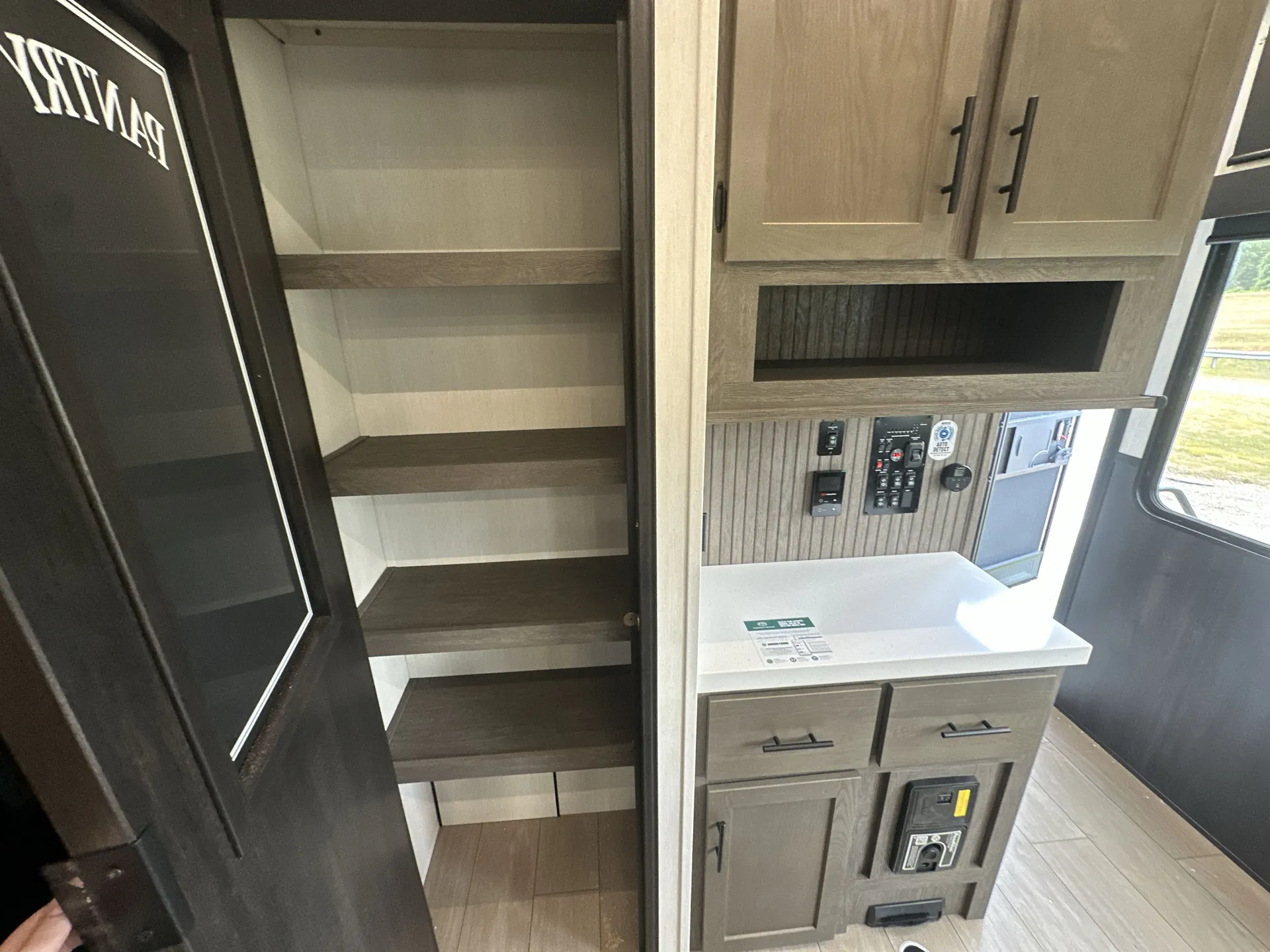 2026 Forest River Arctic Wolf 38LEAH.G — Open tall shelving compartment beside a control panel and countertop near the fifth wheel entry
