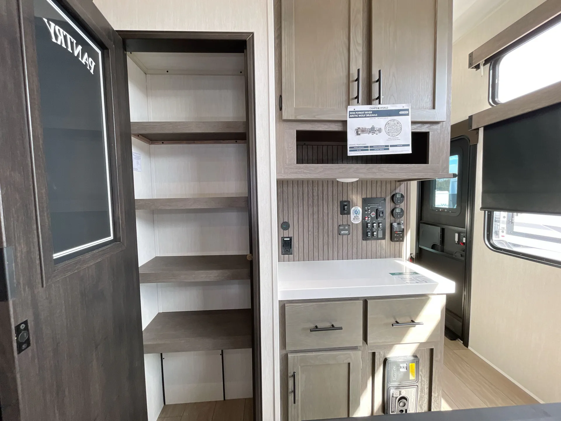 2026 Forest River Arctic Wolf 38LEAH.G — Fifth wheel utility control area with electrical panels, switches, gauges, cabinetry, counter, and an open pantry beside it