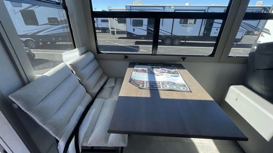 2026 Grand Design Solitude 391DL — Fifth wheel dinette with freestanding table and two upholstered bench seats beneath large windows