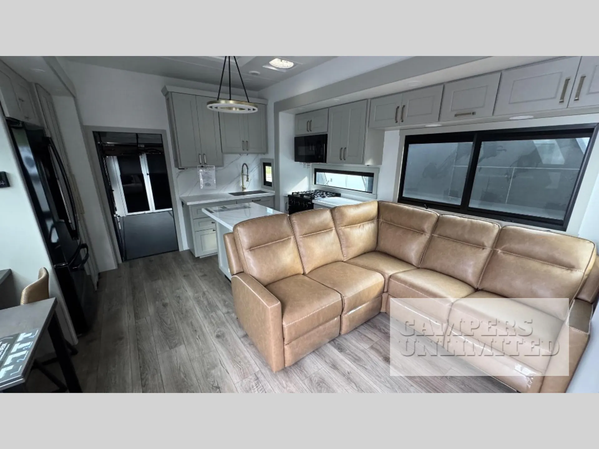 2026 Brinkley Model G 3950 — Large sectional lounge seating fills the foreground beside a kitchen island, appliances, cabinetry, refrigerator, and dining table