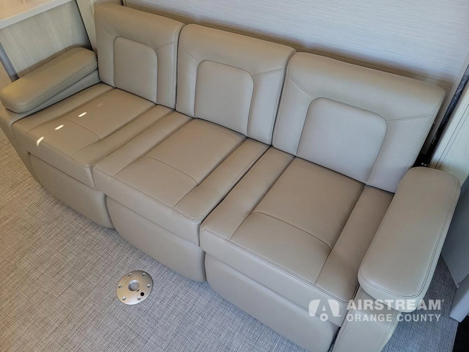 2026 Airstream Atlas Murphy Suite — Wide upholstered lounge sofa with multiple seats, padded armrests, and carpeted floor