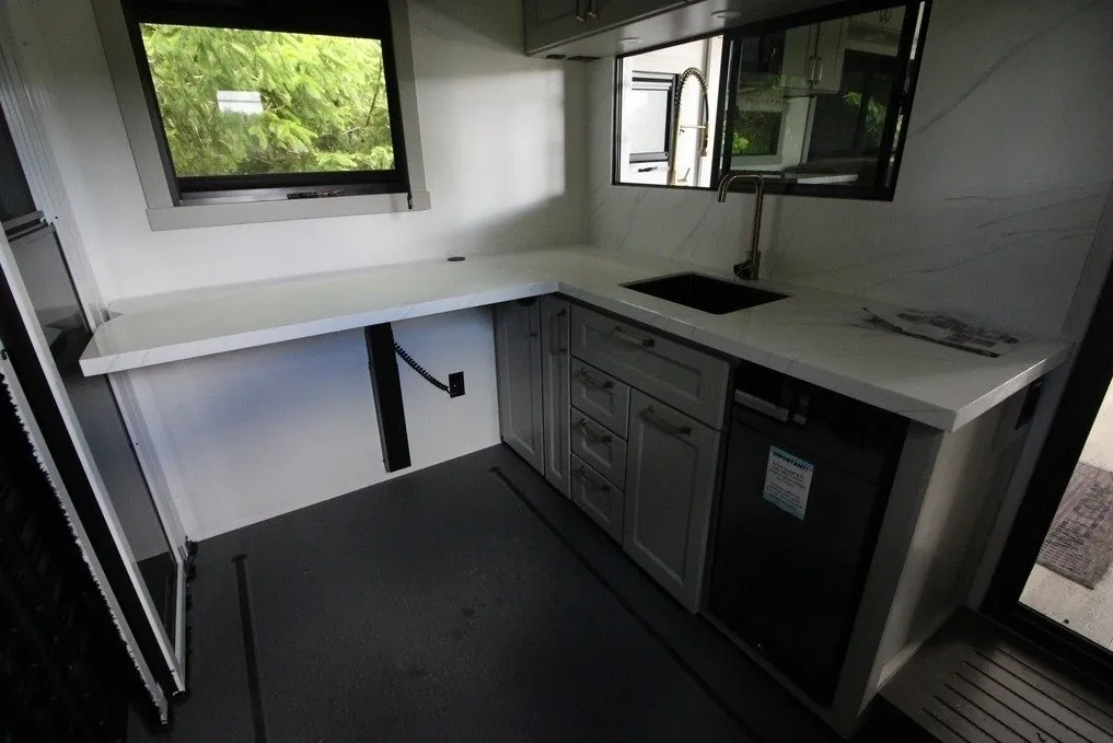 2025 Brinkley Model G 3250 — Fifth wheel garage showing broad dark loading floor, utility sink, refrigerator, and surrounding counters