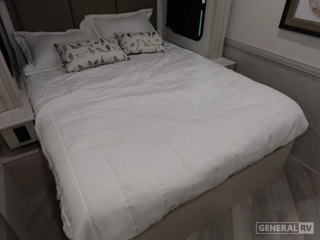 2026 Holiday Rambler Invicta 36Y — Main bedroom bed with white bedding, pillows, side nightstands, window, and wood-look flooring