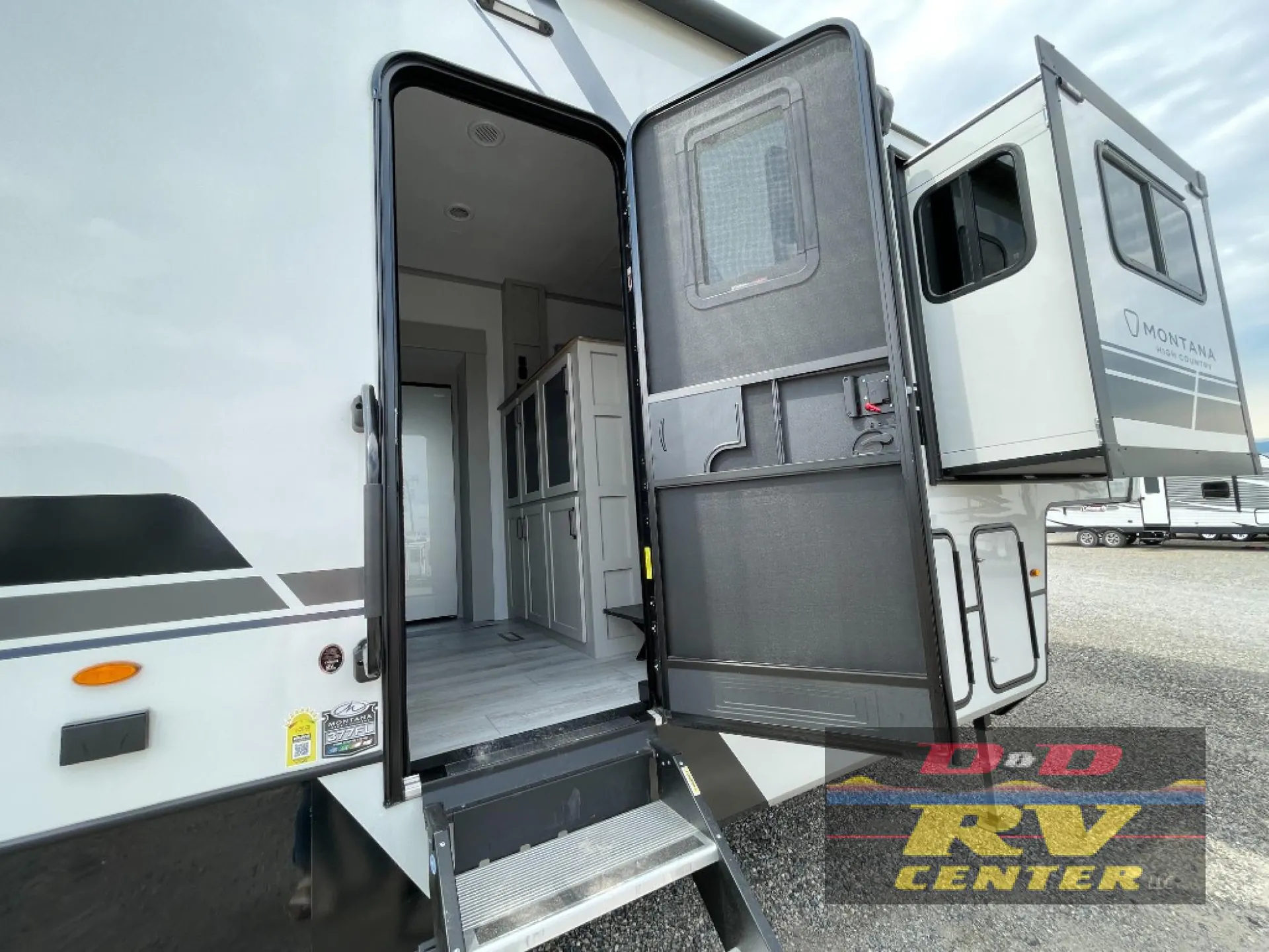 2026 Keystone Montana High Country 377FL — Fifth-wheel entry door and folding steps open to a visible interior hallway with cabinetry and flooring