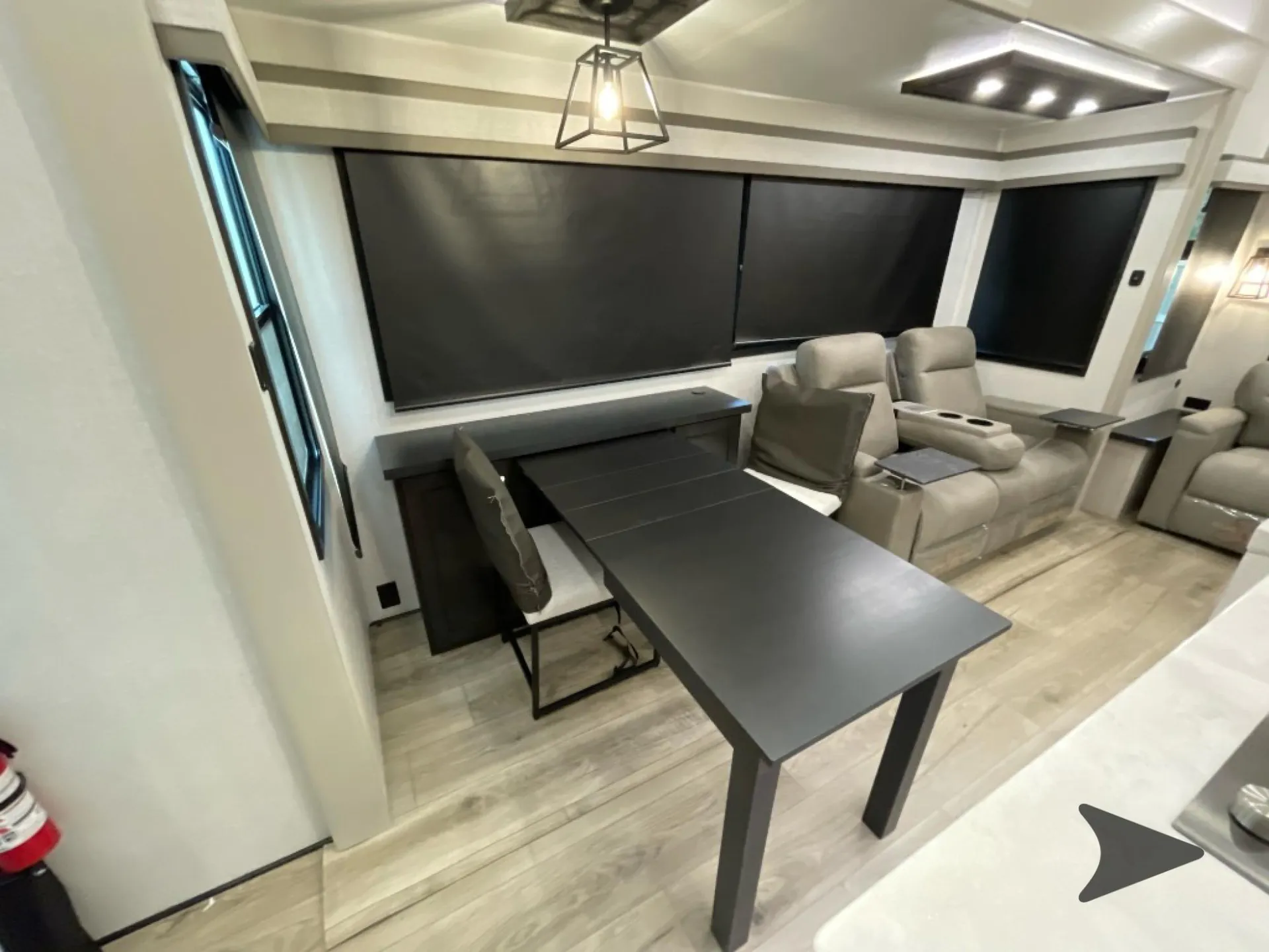 2026 Jayco North Point 377RLBH — Fifth wheel dining table and bench beside recliners, with kitchen counter edge and window seating visible