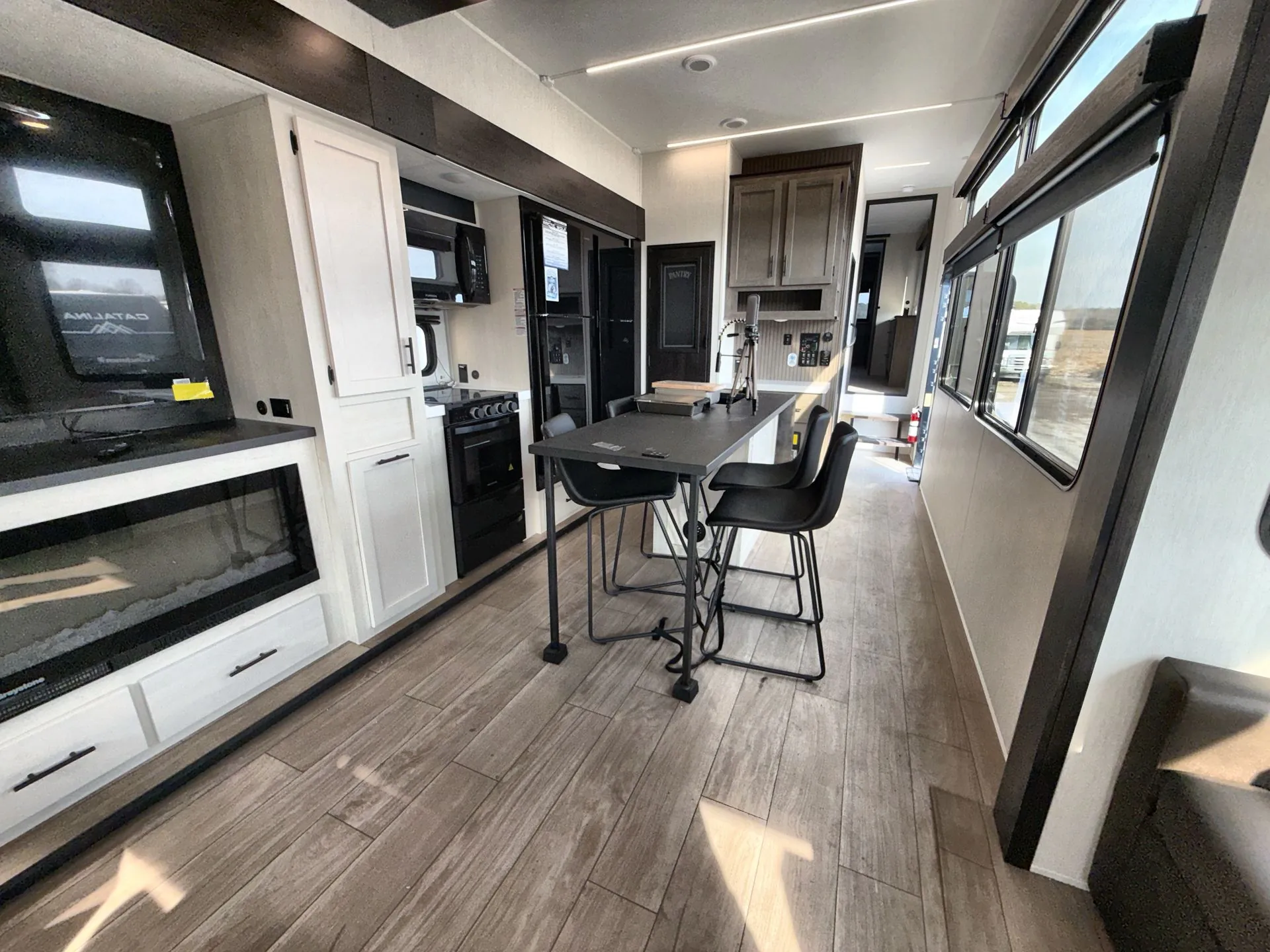 2026 Forest River Arctic Wolf 38LEAH.G — Fifth wheel overview with central dining table, kitchen appliances, fireplace, and lounge seating