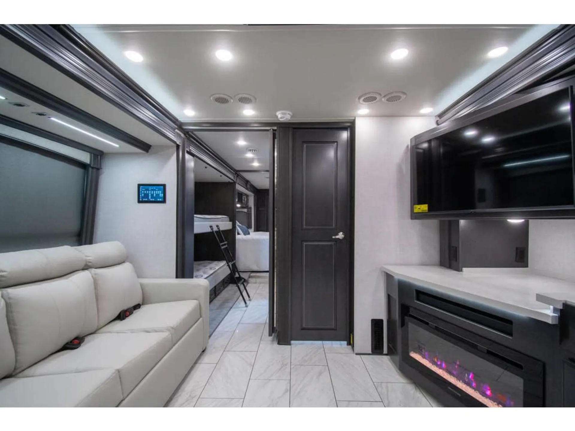 2026 Fleetwood Discovery LXE 40G — Class A lounge with a recliner sofa, fireplace and television, opening toward the kitchen and rear sleeping area