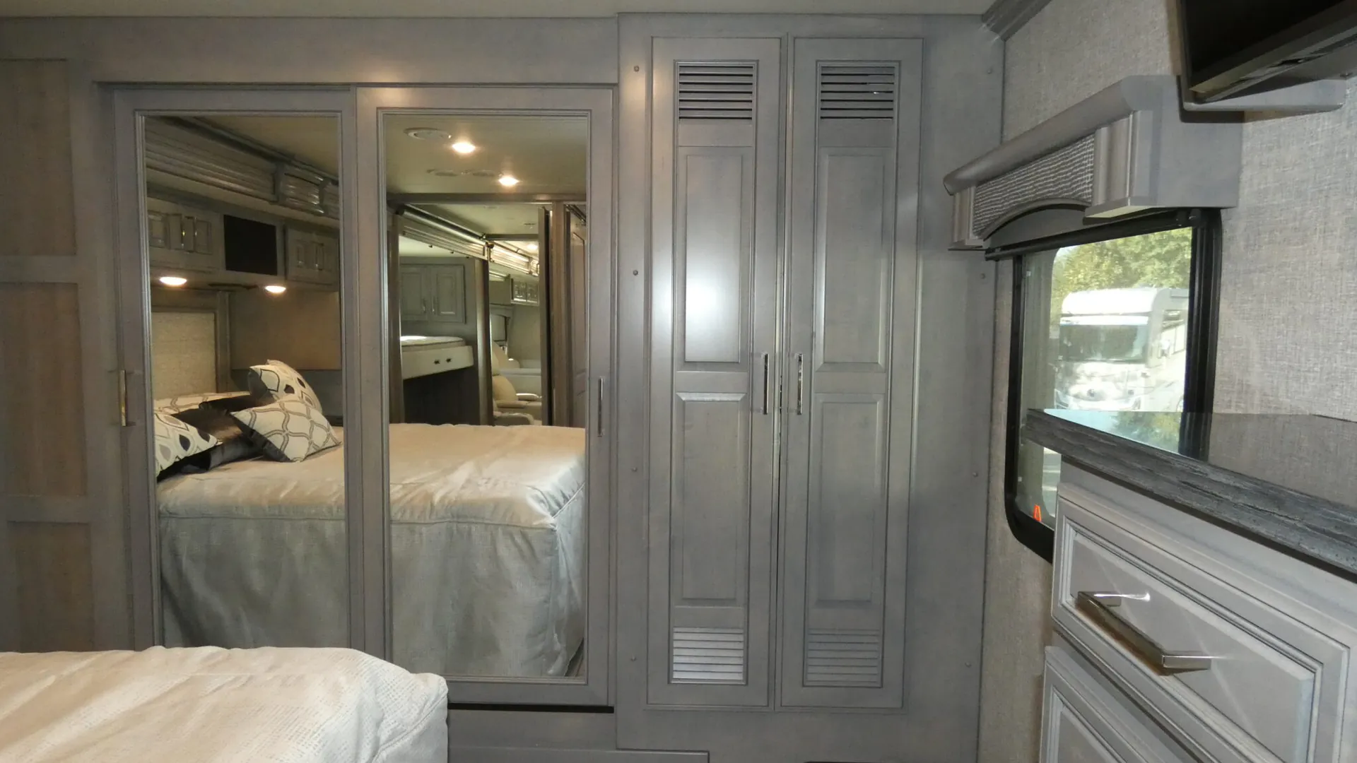 2026 Fleetwood Discovery LXE 40G — Main bedroom with a bed, mirrored wardrobe doors, tall closets, window, and dresser
