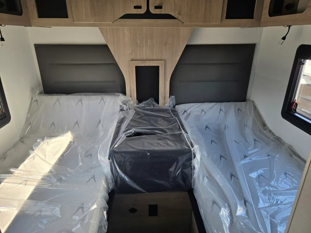 2027 Grand Design Lineage Series F 29AN5 — Main bedroom with two side-by-side mattresses, center upholstered divider, overhead cabinets, and reading lights