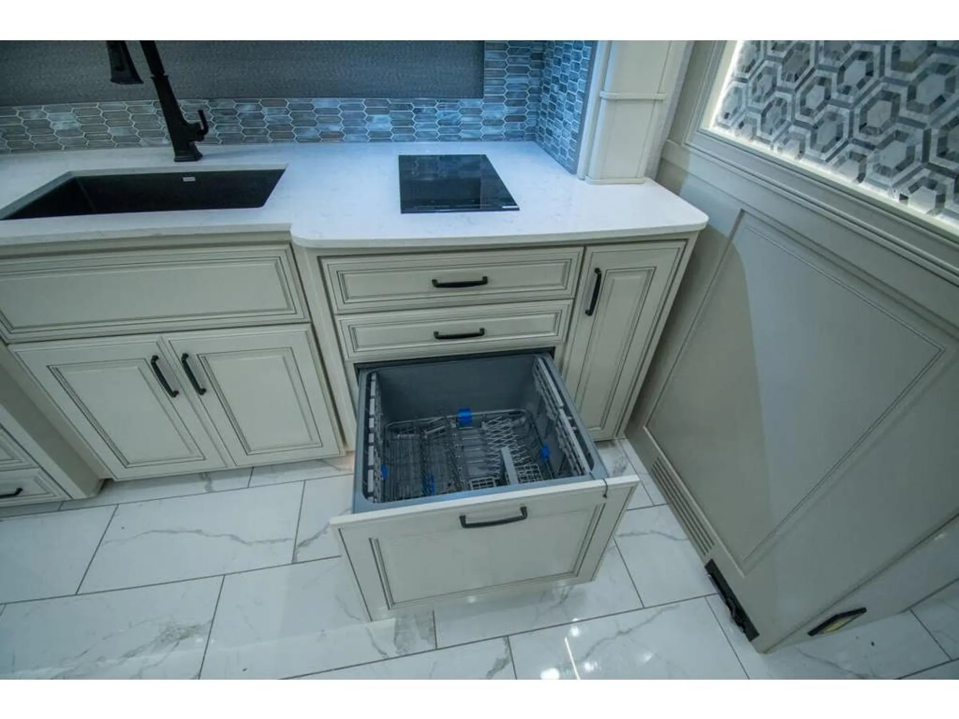 2026 American Coach American Dream 45A — Kitchen counter with sink, cooktop, dishwasher drawer, white cabinetry, and patterned backsplash