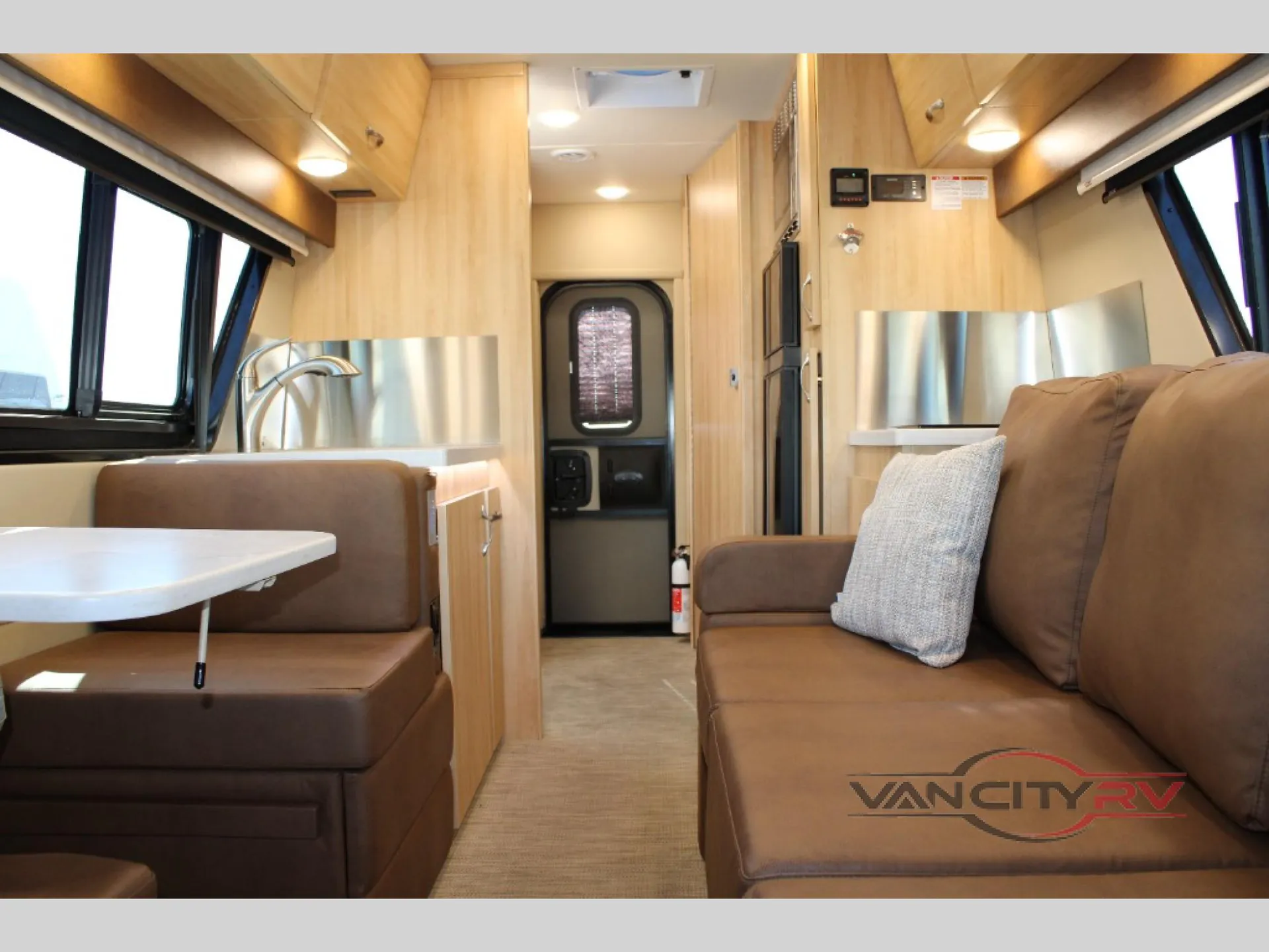 2024 Chinook RV Maverick SS — Class B van interior with a sofa, dinette table and bench, kitchenette sink, overhead cabinets, and central aisle