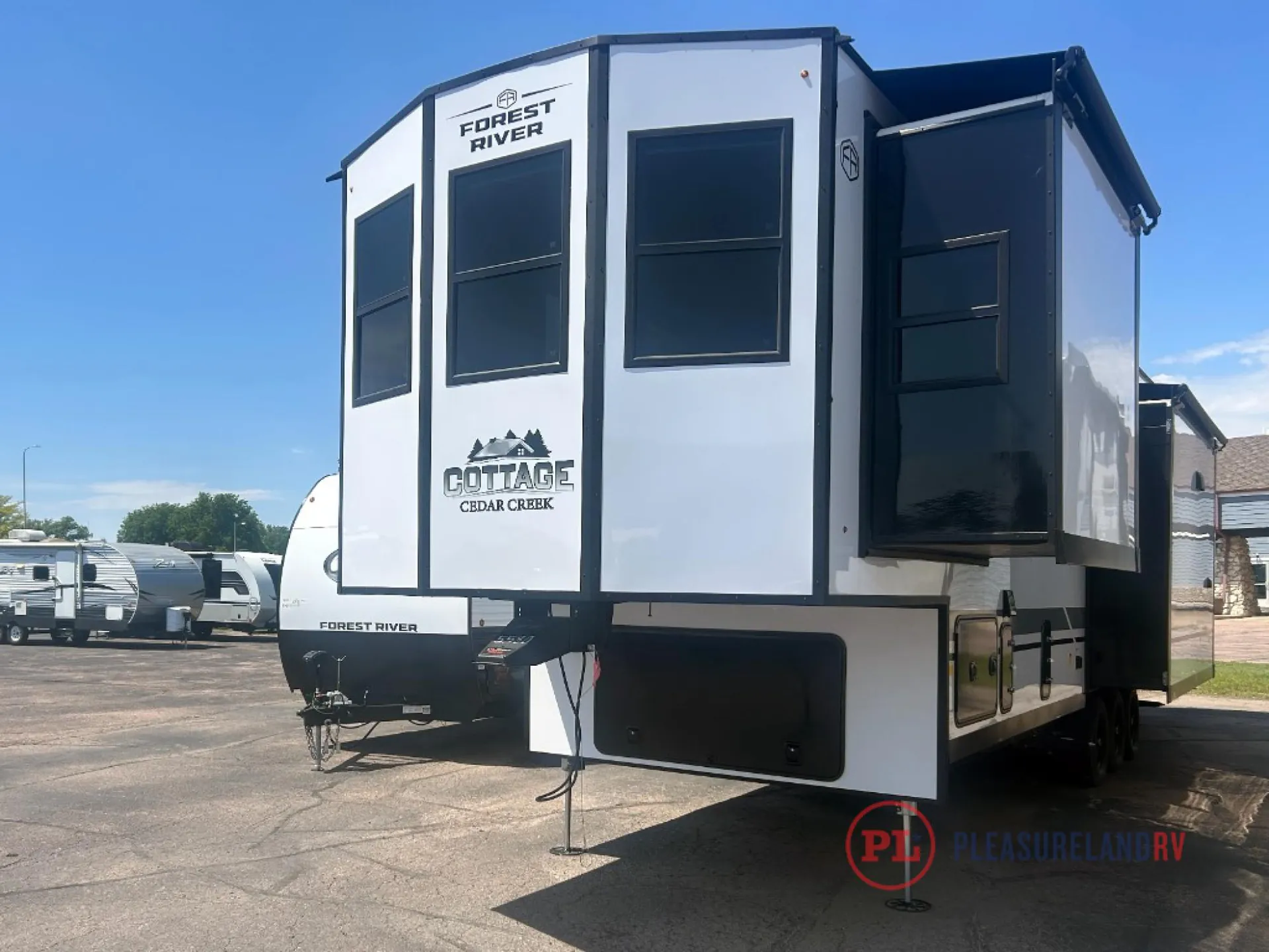 2026 Forest River Cedar Creek Cottage 41FWC — Exterior three-quarter view visibly shows the RV front hitch, side walls, slide-out, windows, and lower access doors