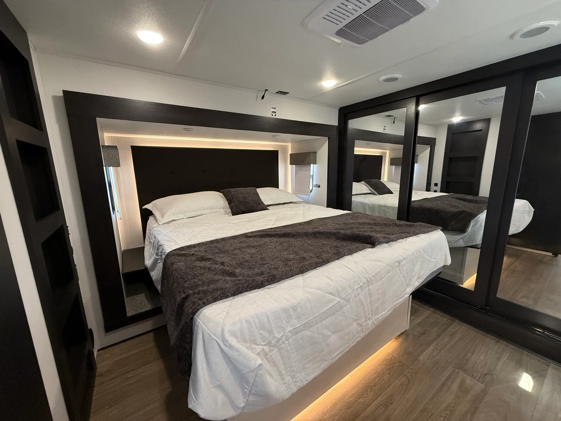 2027 Forest River Sabre 38RVHUNTER — Fifth wheel bedroom with king bed, illuminated headboard, mirrored wardrobe doors, and wood-look flooring