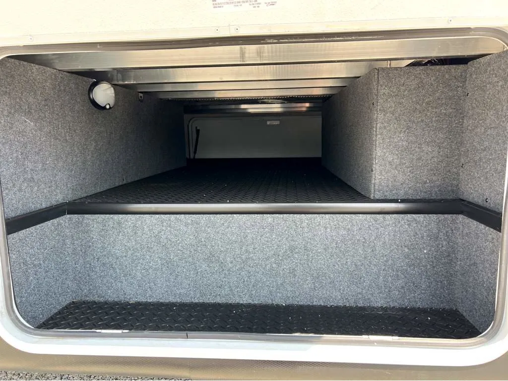 2025 Jayco Seismic Luxury Series 4113 — Visible exterior pass-through storage compartment with carpeted walls and cargo floor